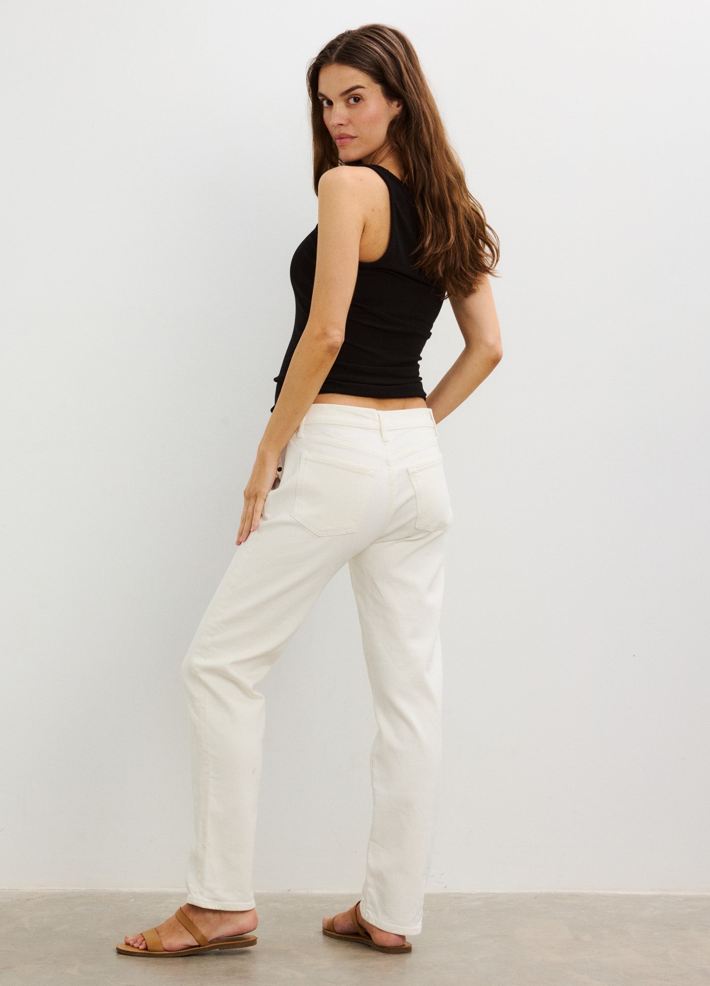 Black ribbed maternity tank top with wide straps, fitted silhouette, styled with off-white straight-leg pants and tan.