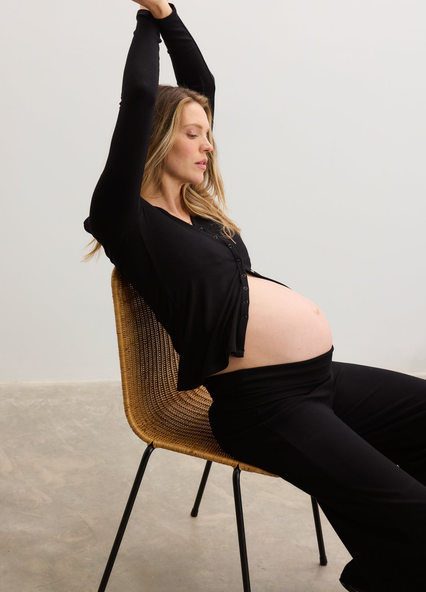 Black rib-knit nursing cardigan with long sleeves worn open over a maternity belly.