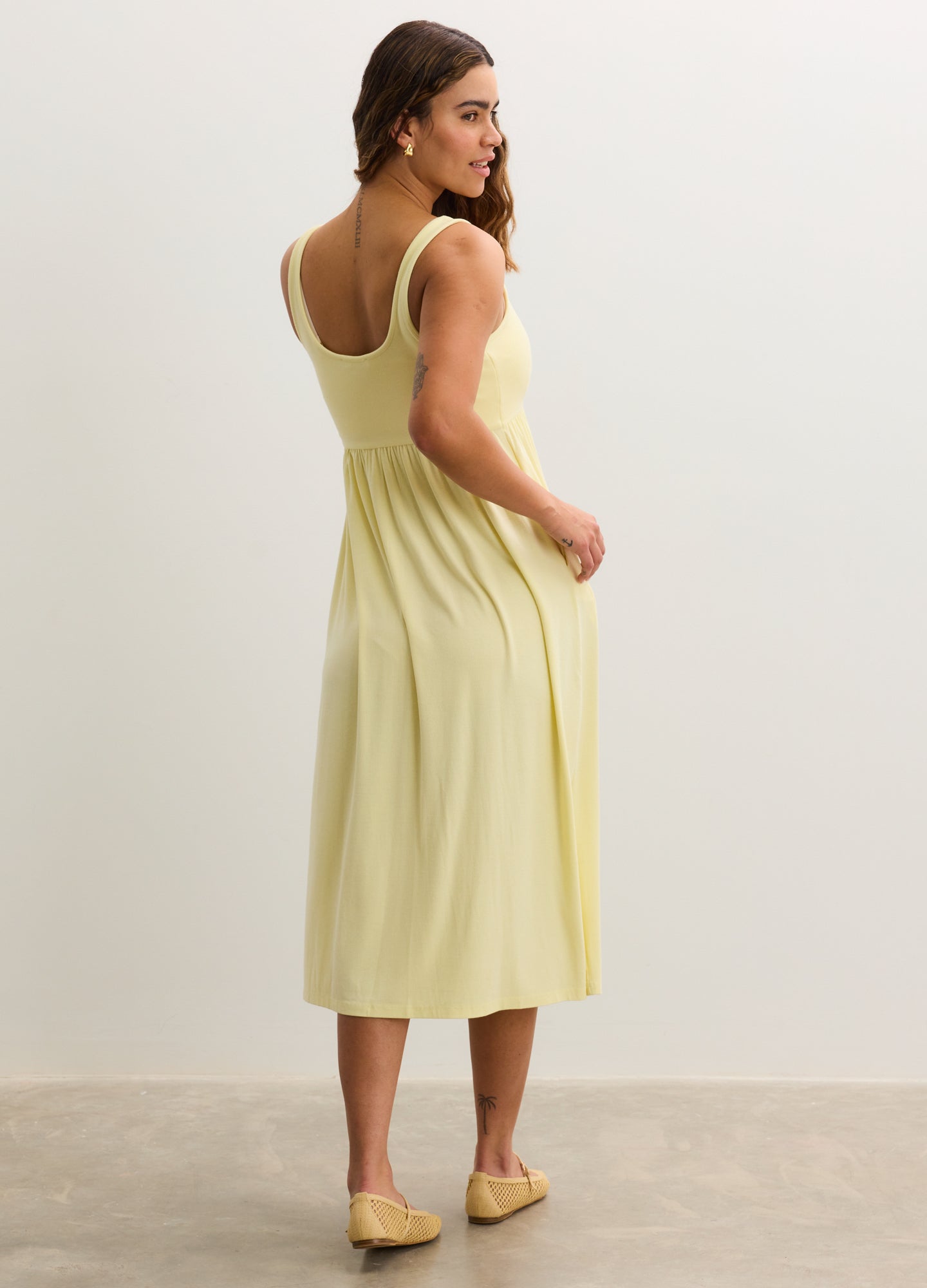 Soft yellow ribbed nursing tank dress with scoop back and midi length, worn by pregnant model.