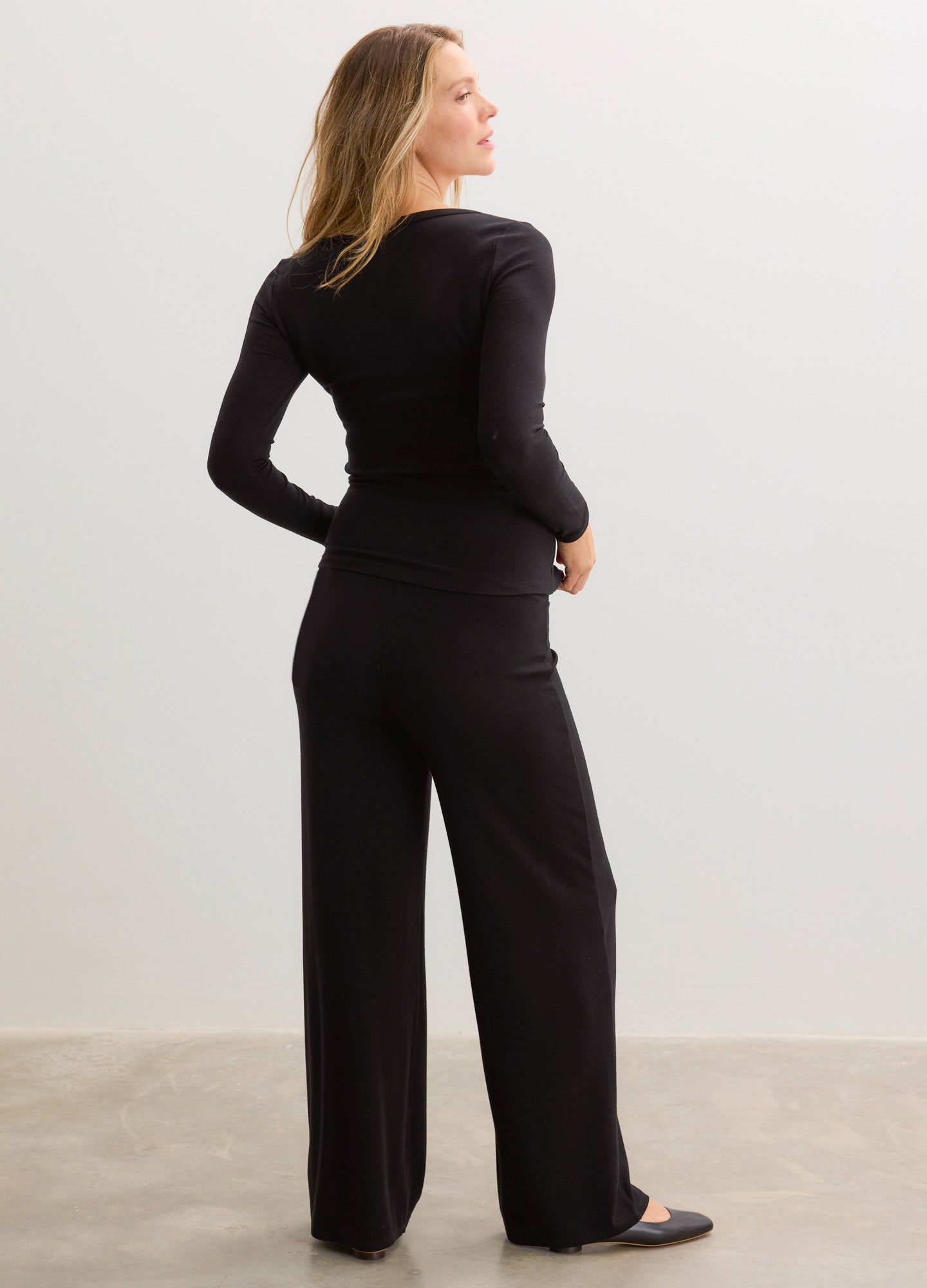 Black ribbed maternity pants with relaxed wide legs and over-under waistband styled for pregnancy comfort.