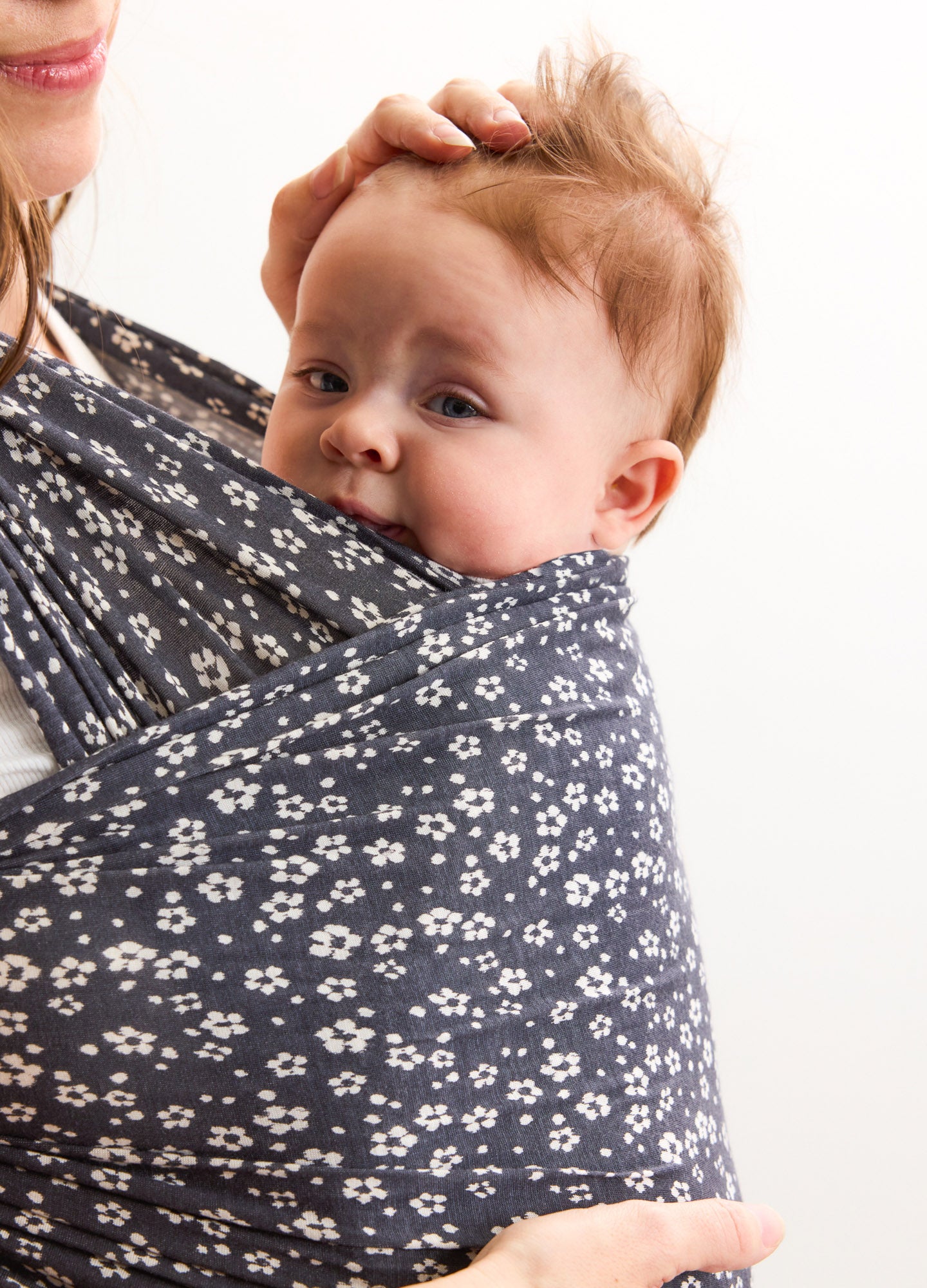 Navy blue maternity wrap with white ikat bloom pattern holding baby close.