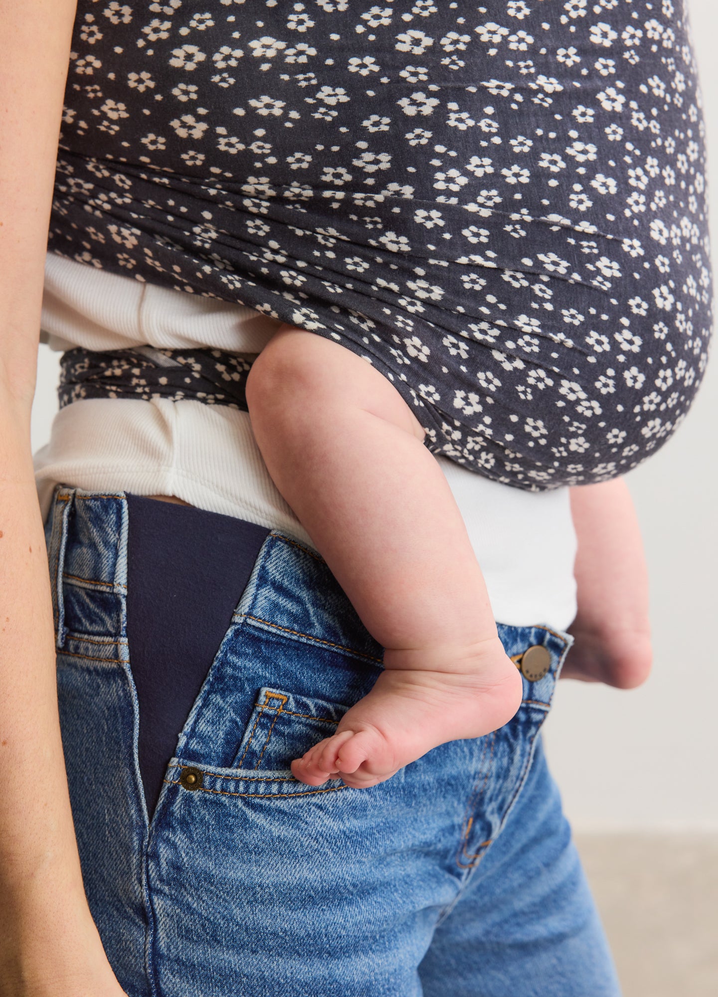 Soft navy and white ikat floral baby wrap securely holding an infant against a maternity outfit.