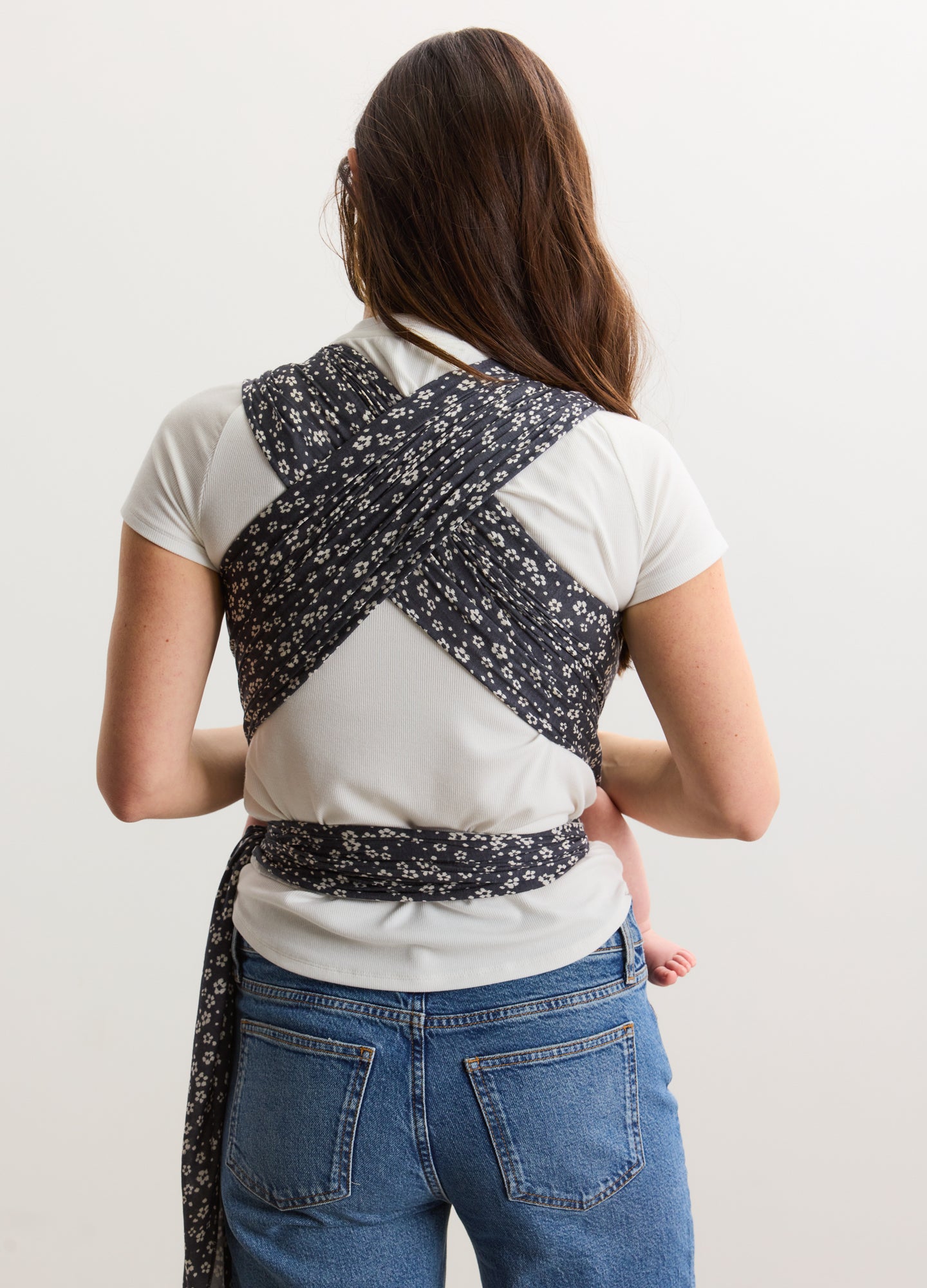 Navy blue and white floral patterned baby wrap worn cross-back over white T-shirt and jeans for maternity use.