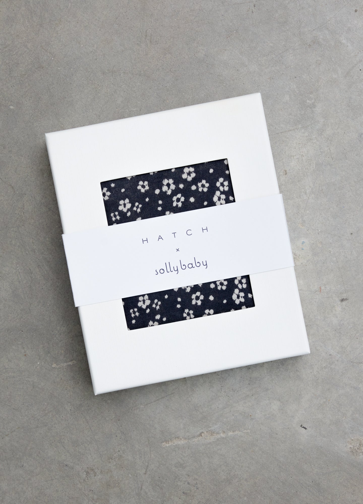 Navy blue maternity wrap with white ikat floral pattern, soft lightweight fabric in white box packaging.