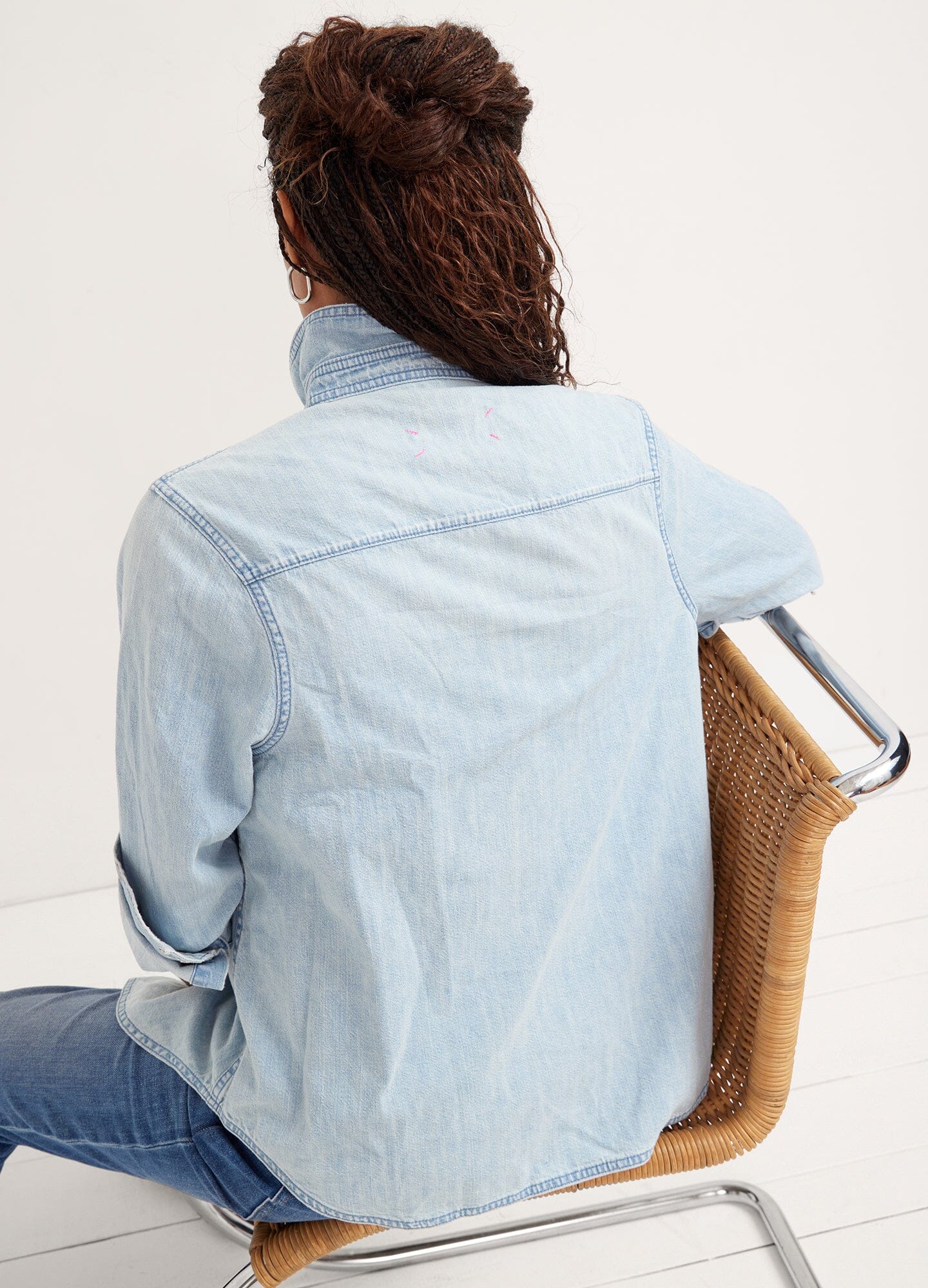 The Denim Maternity Shirt - Light wash denim maternity shirt with rolled sleeves, worn open over a white tank top during pregnancy.