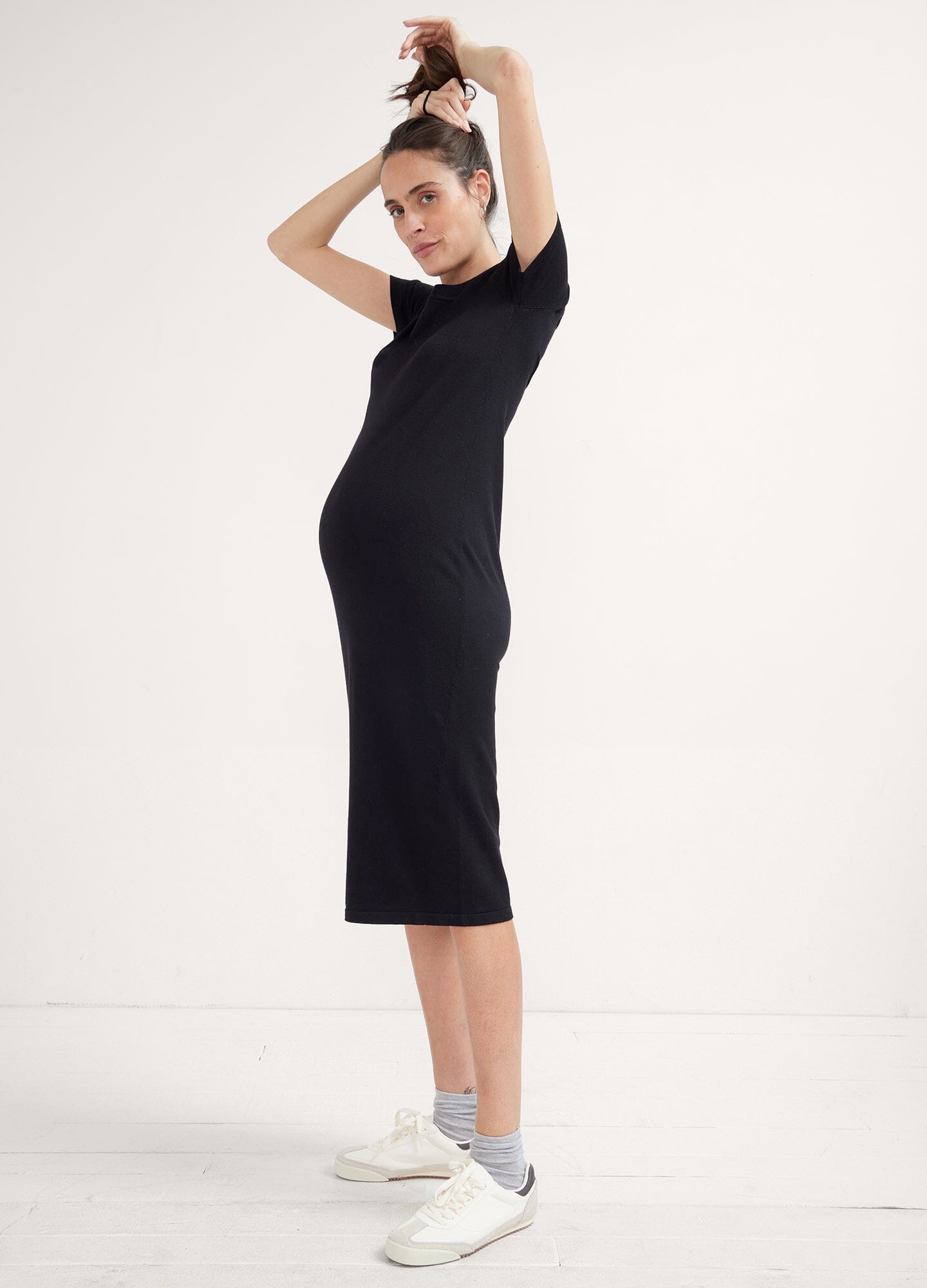 The Eliza Dress POS - Black short-sleeve maternity dress with nursing-friendly design and fitted silhouette, styled with tall black boots.