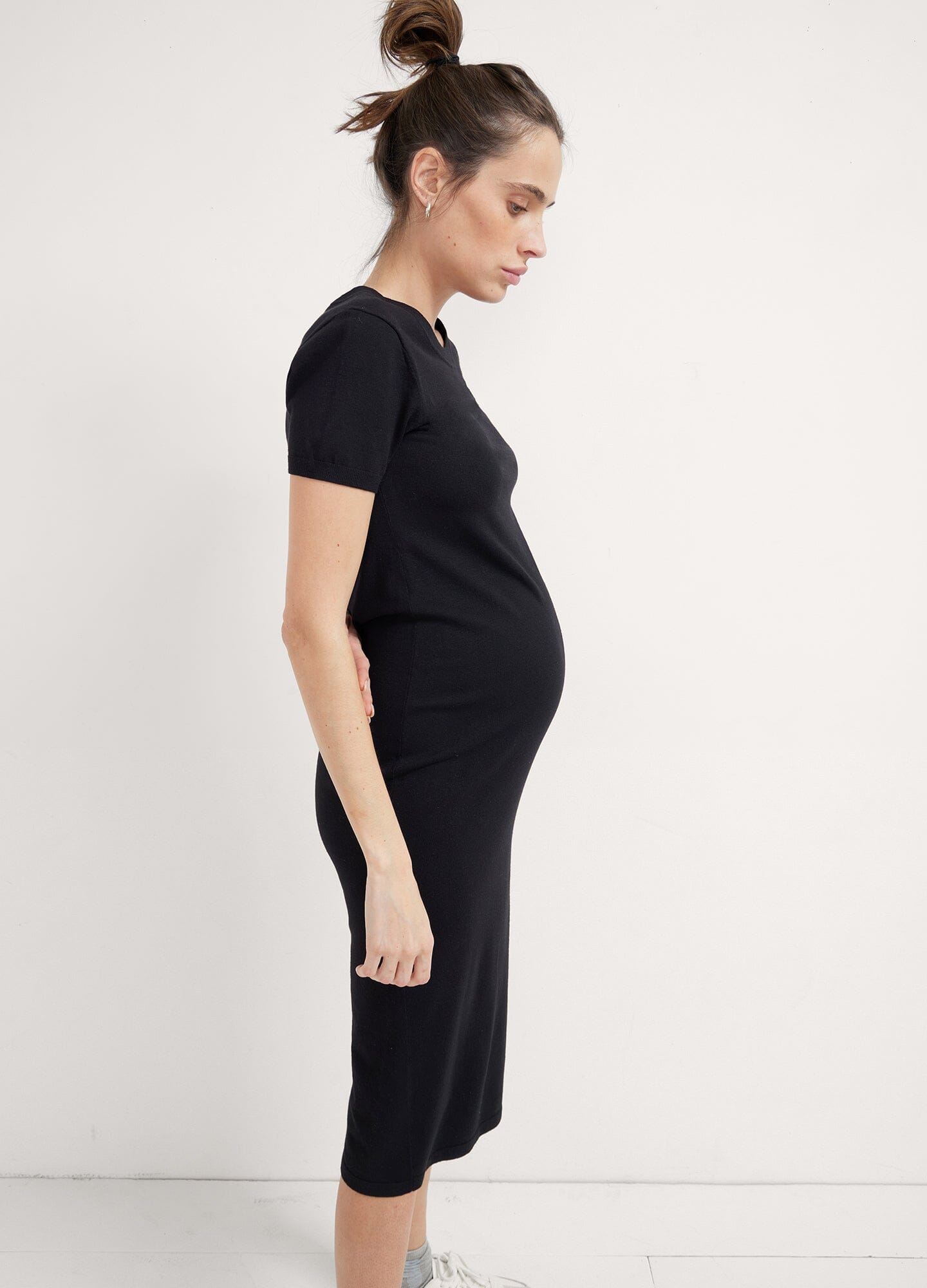The Eliza Dress POS - Black short-sleeve maternity dress with nursing-friendly design and fitted silhouette, styled with tall black boots.