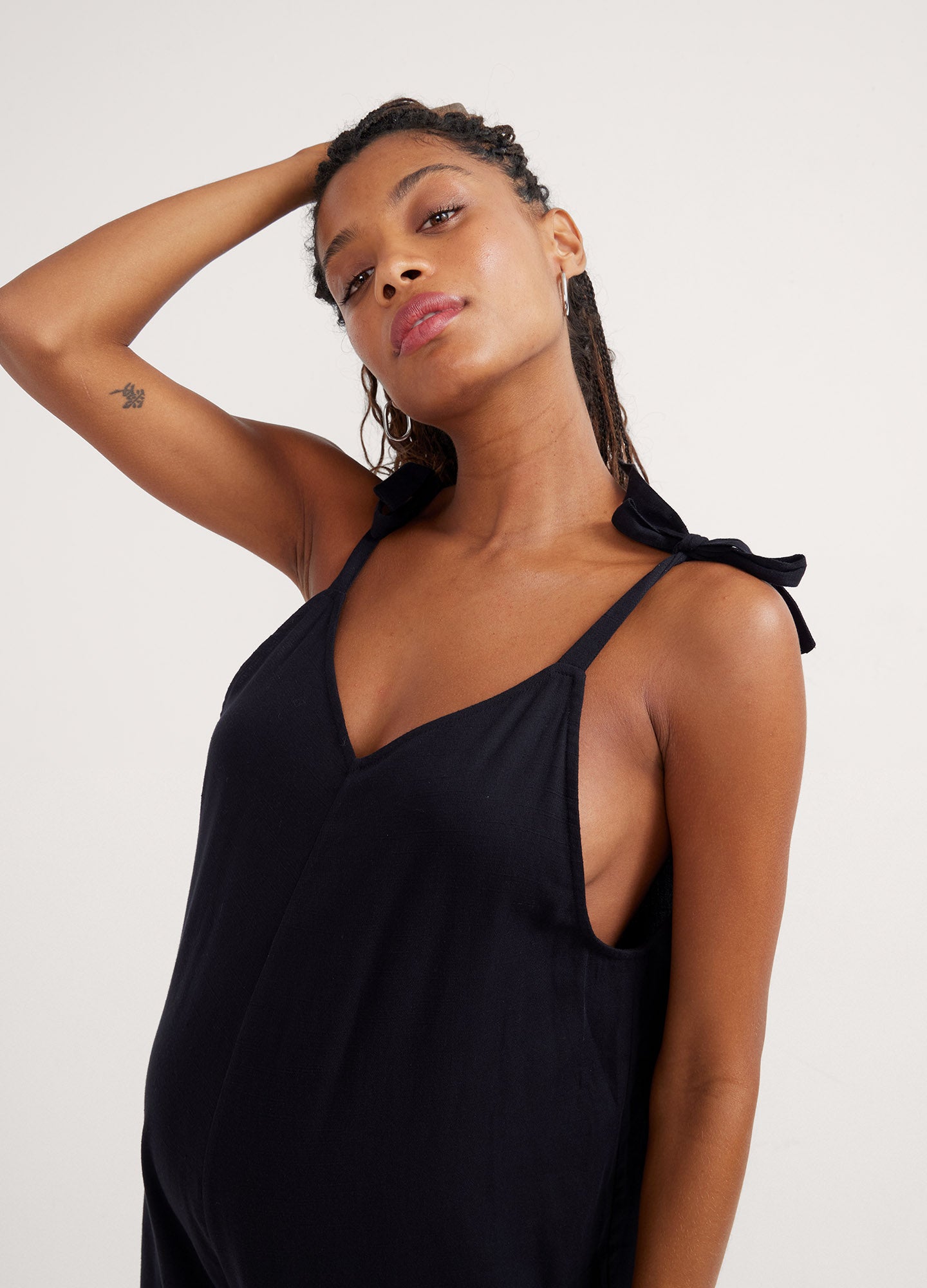 Black maternity jumpsuit with deep V-neck and thin adjustable straps, loose fit around the waist.