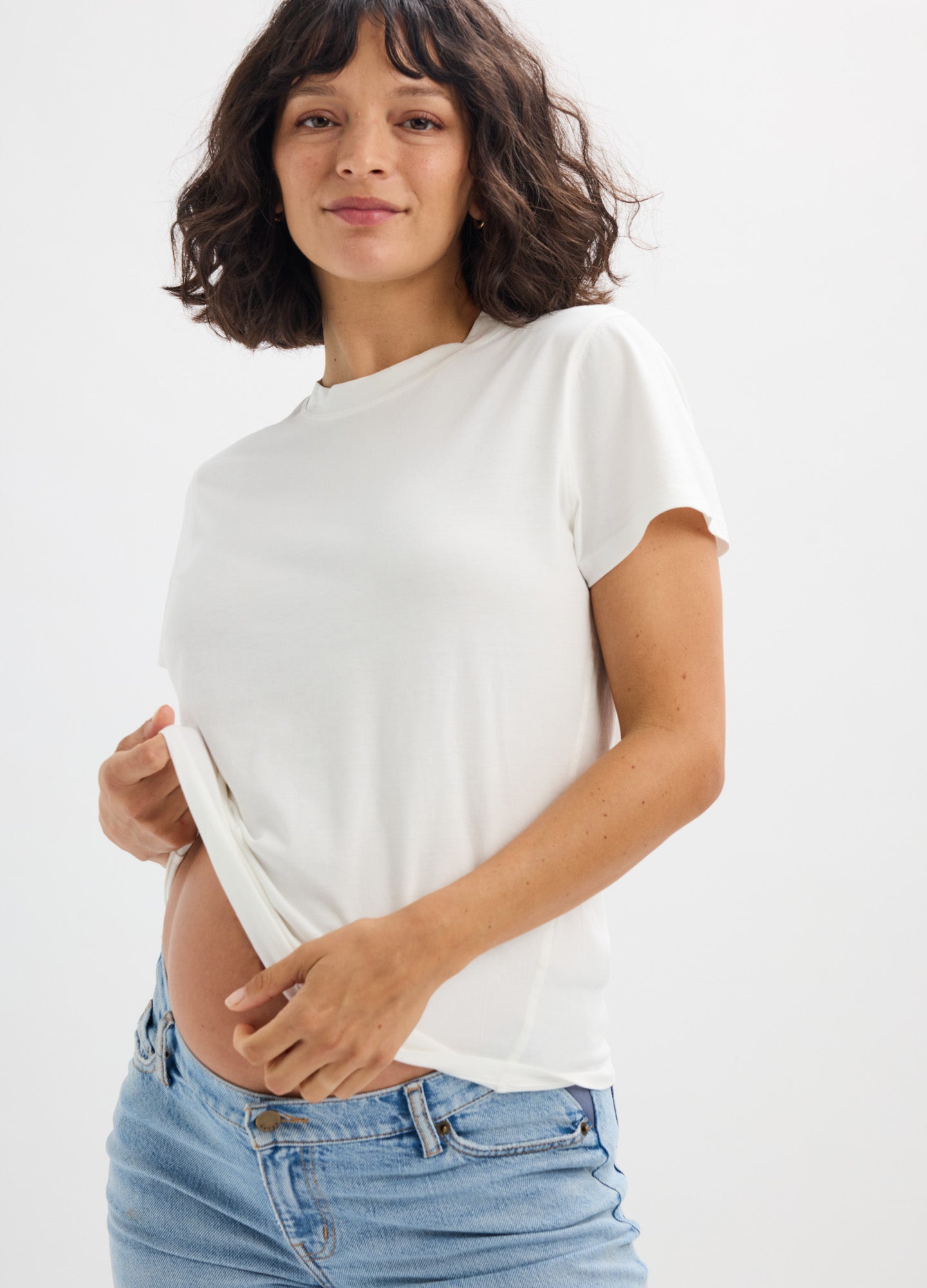 Soft white short-sleeve maternity tee with scalloped edges, worn by a pregnant woman.
