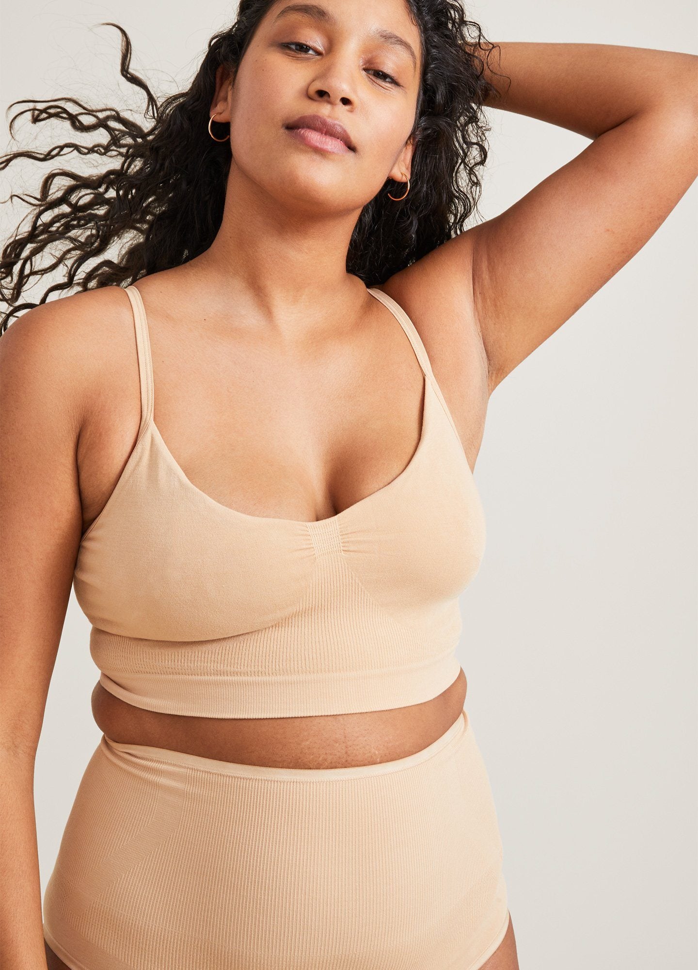 Beige seamless maternity pumping bra with thin adjustable straps and soft fabric design.