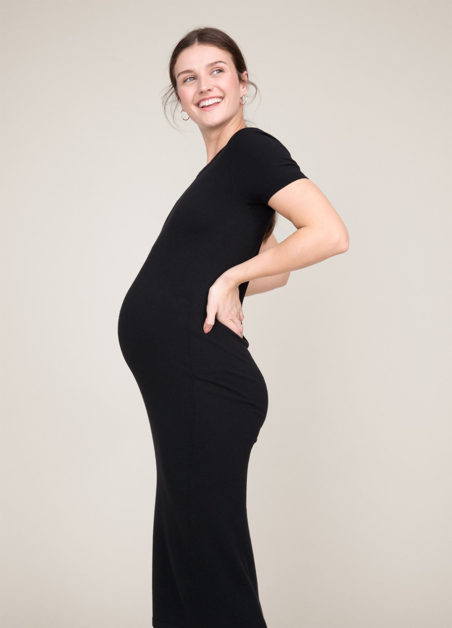 The Eliza Dress POS - Black short-sleeve maternity dress with nursing-friendly design and fitted silhouette, styled with tall black boots.