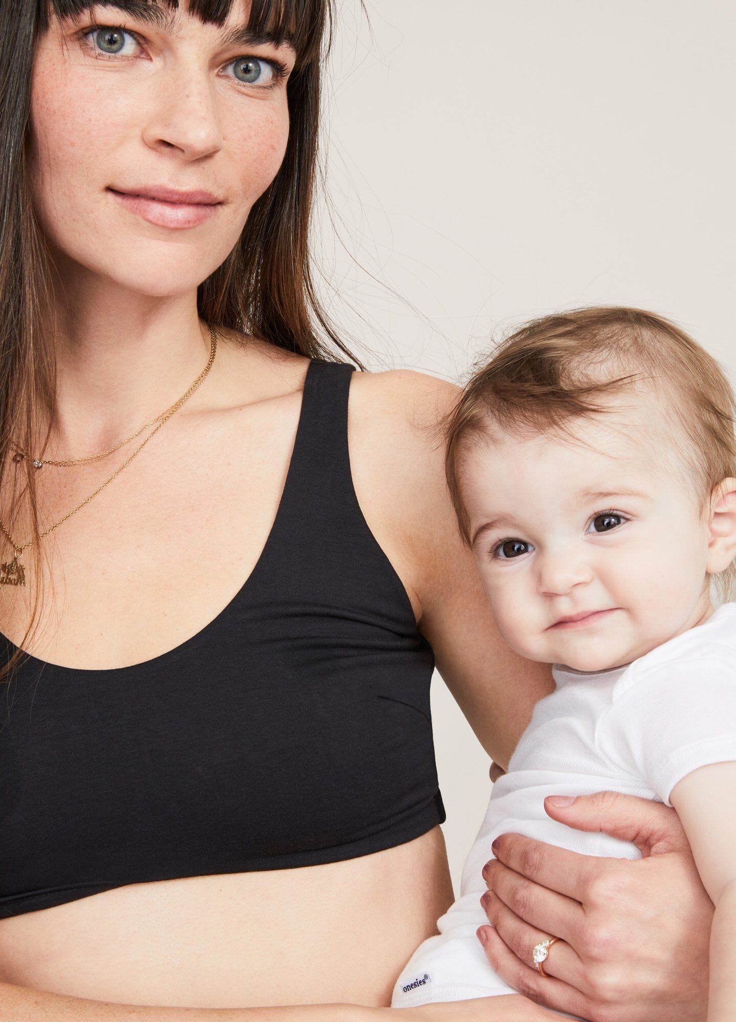 Black seamless maternity bra with wide straps and soft fabric, modeled by a woman holding a baby.