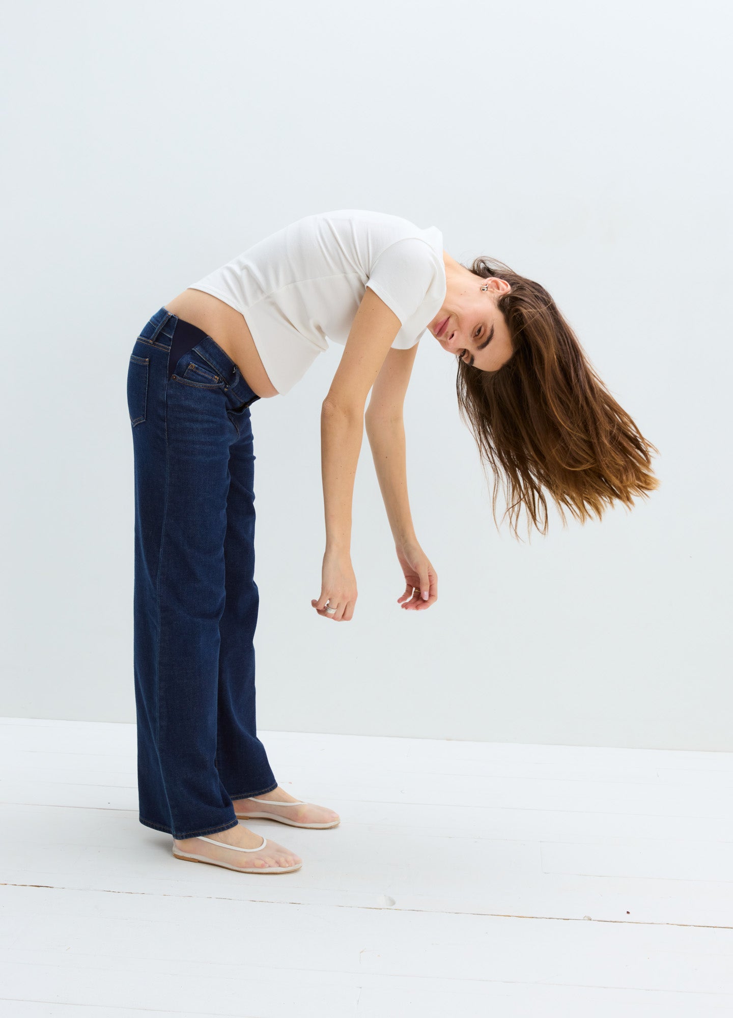 Dark blue wide leg maternity jeans with a relaxed fit, worn by a pregnant model bending forward.