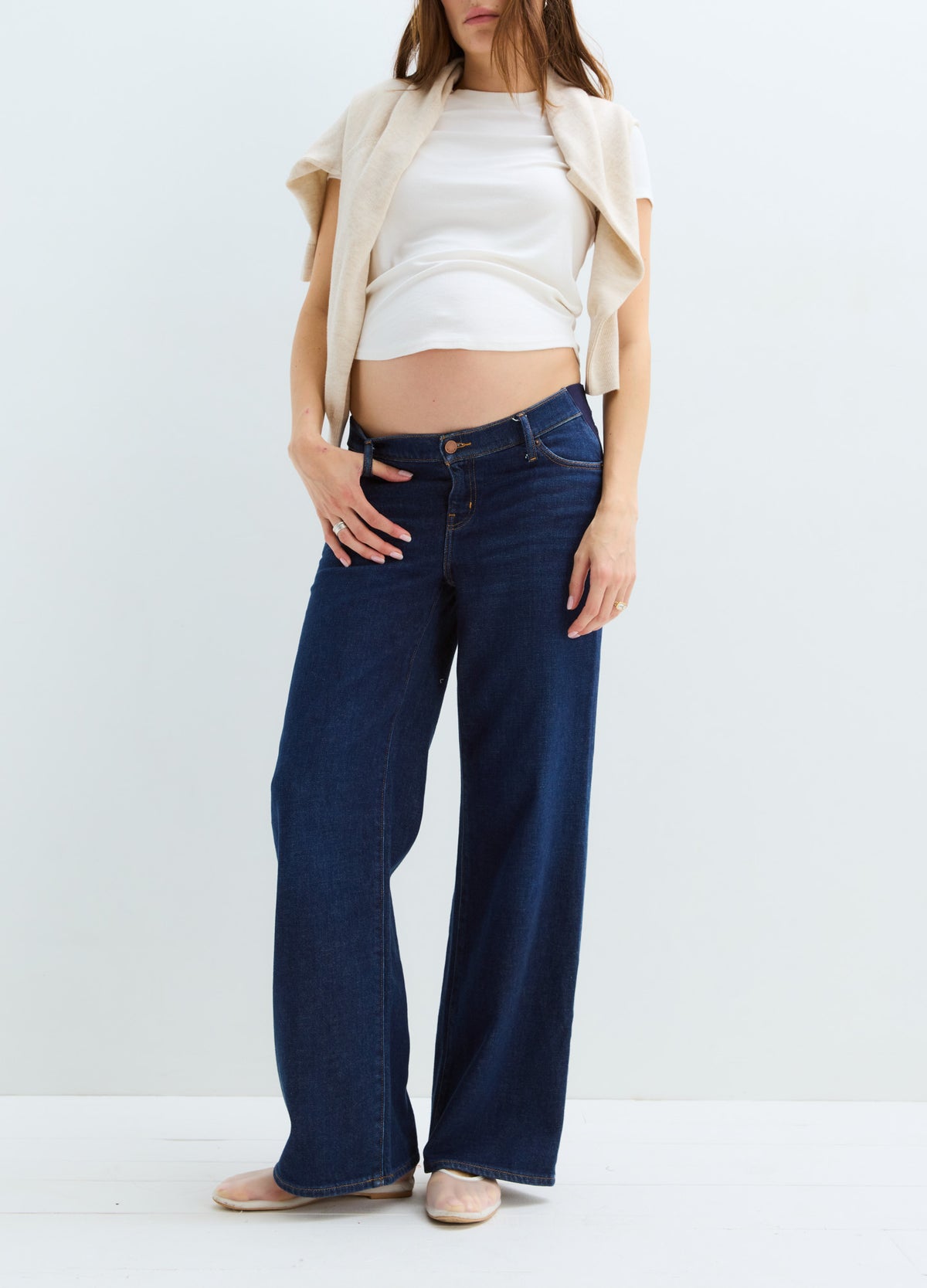 Dark blue wide-leg maternity jeans with a relaxed fit and adjustable waist, worn by a pregnant woman.