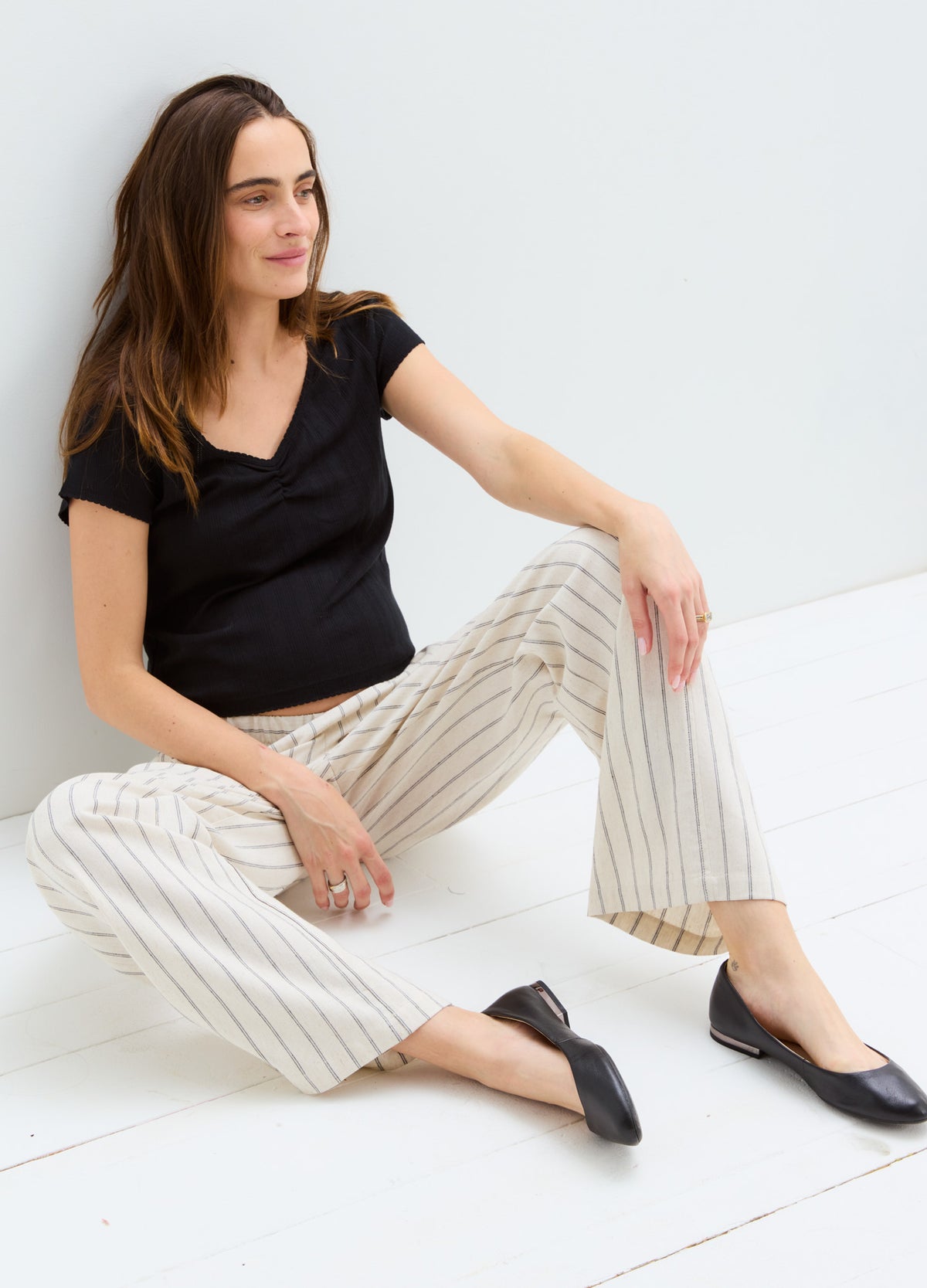 Black short-sleeve maternity tee with sweetheart neckline, paired with cream striped wide-leg pants.