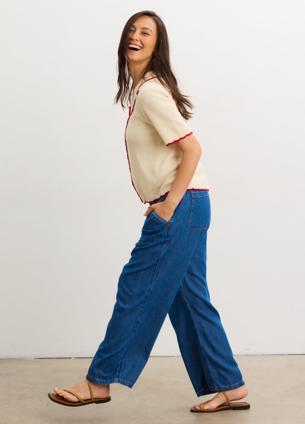 Blue wide-leg maternity denim pants with high waist and relaxed fit modeled with beige short-sleeve top and sandals.