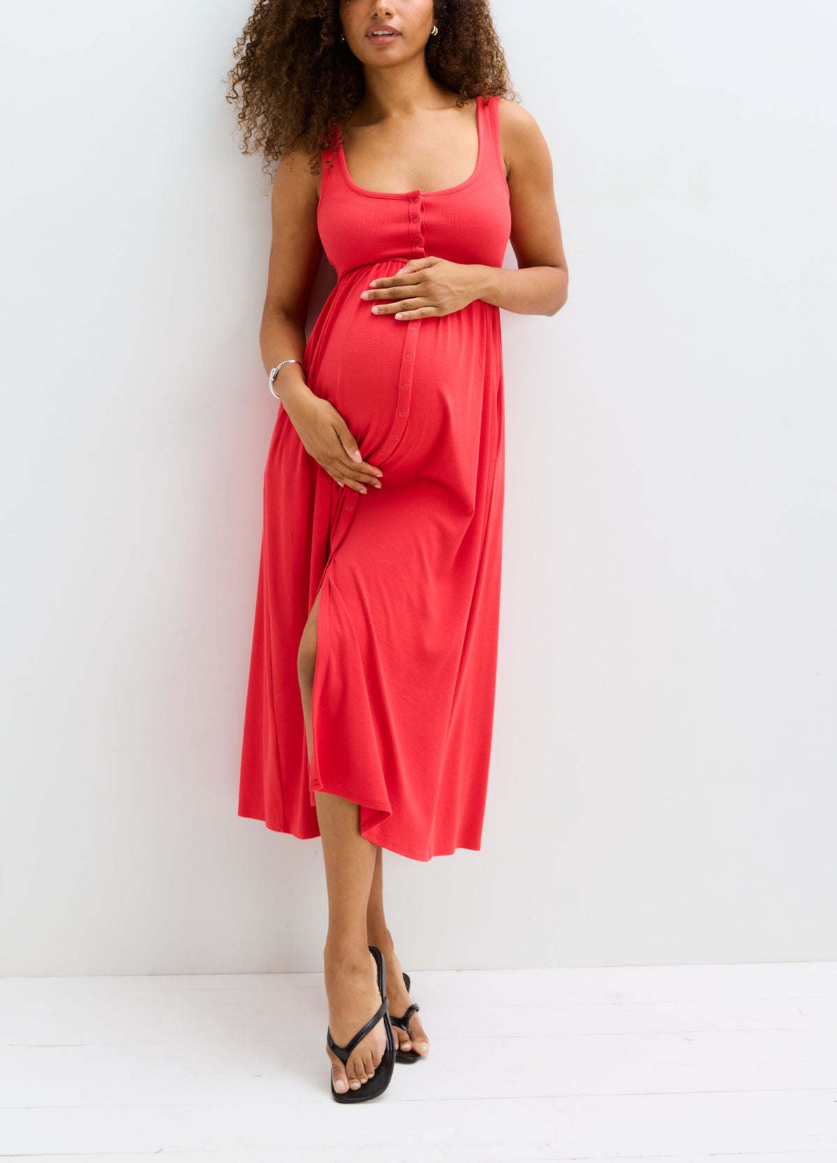 Red ribbed maternity tank dress with scoop neck, side slit, and sleeveless design.