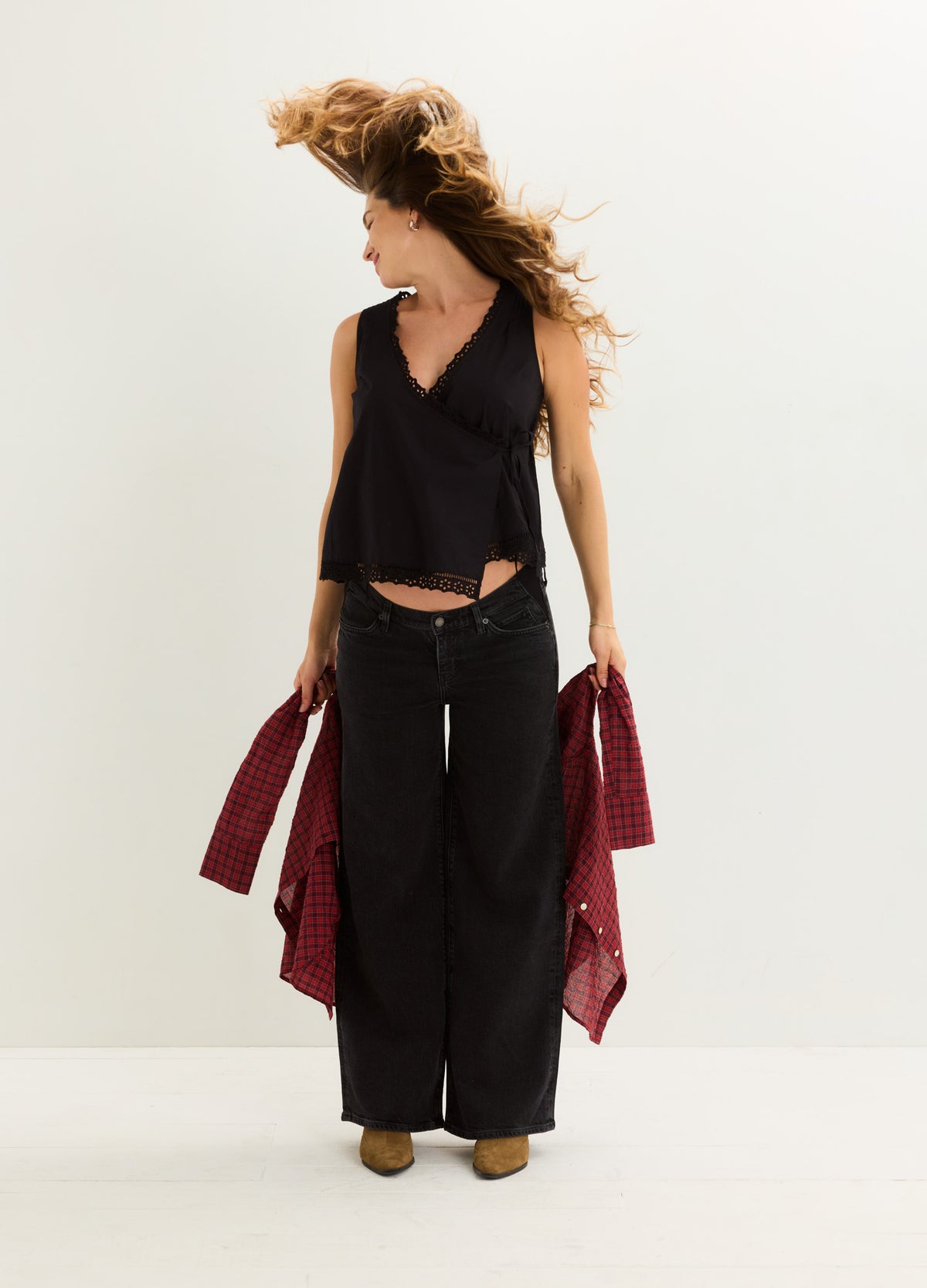 Black sleeveless maternity nursing top with V-neck and relaxed fit, paired with wide-leg black pants and brown shoes.