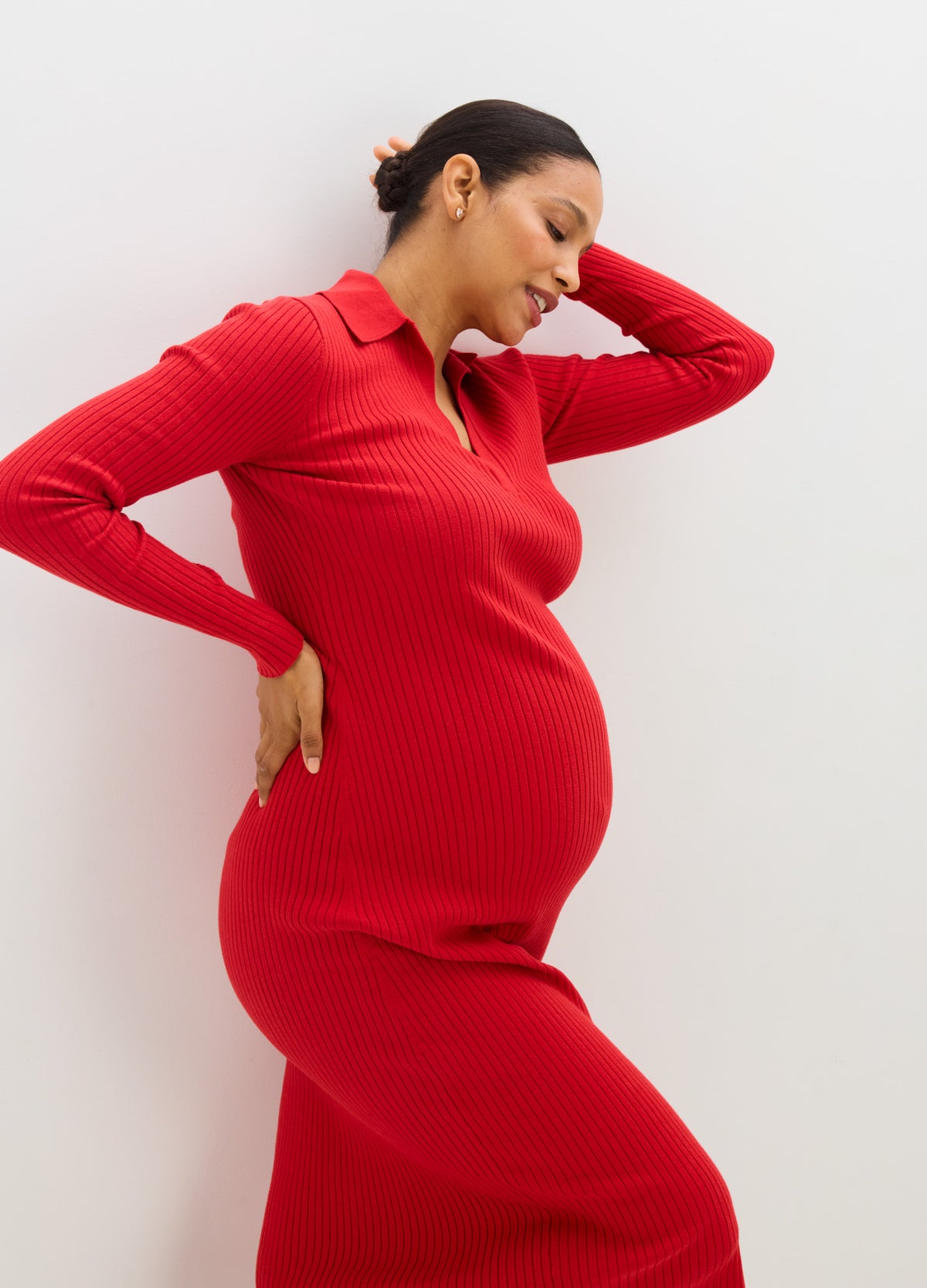 Red ribbed knit maternity sweater dress with collar and long sleeves, fitted over pregnant belly.