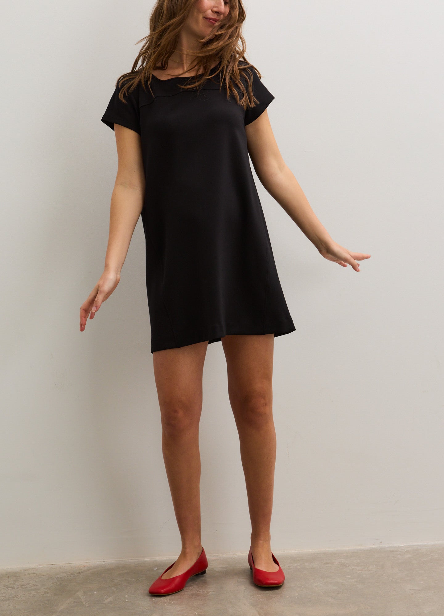 Black short-sleeve maternity dress with a loose, flattering A-line silhouette paired with red ballet flats.