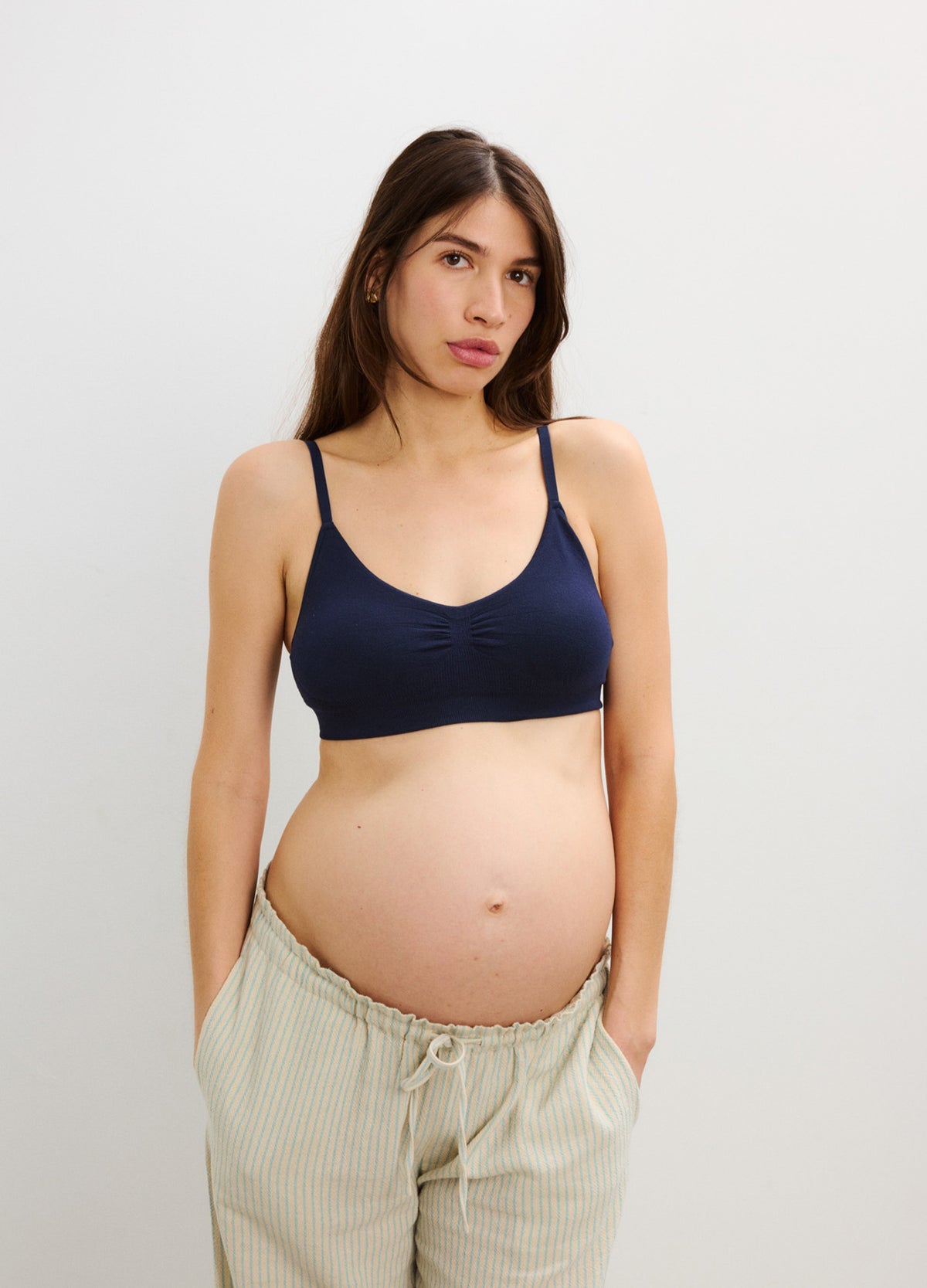 Navy blue seamless maternity bra with wide straps and soft fabric, modeled by a pregnant woman.