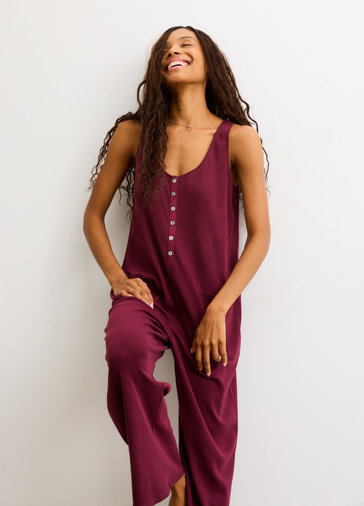Sleeveless plum maternity jumpsuit with button front and relaxed wide-leg fit.