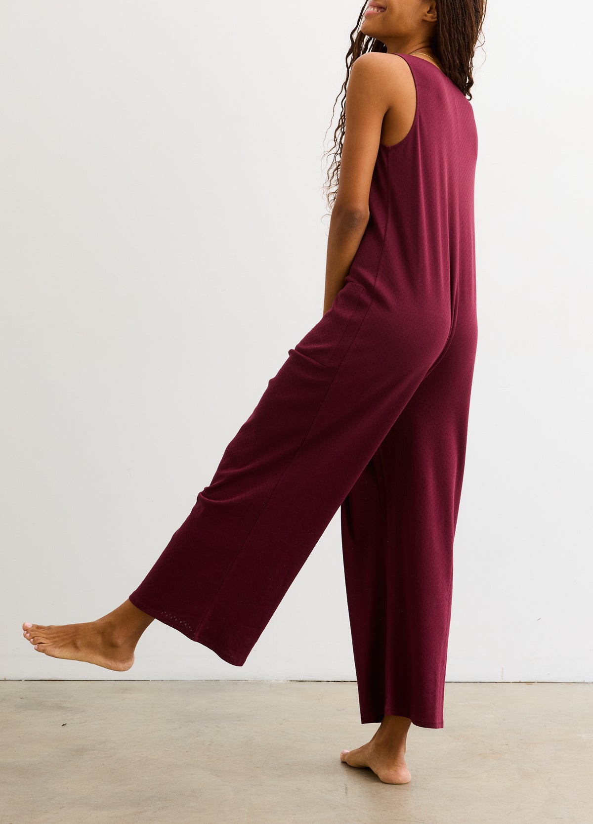 Sleeveless maternity jumpsuit in deep burgundy with a relaxed wide-leg fit and soft fabric.