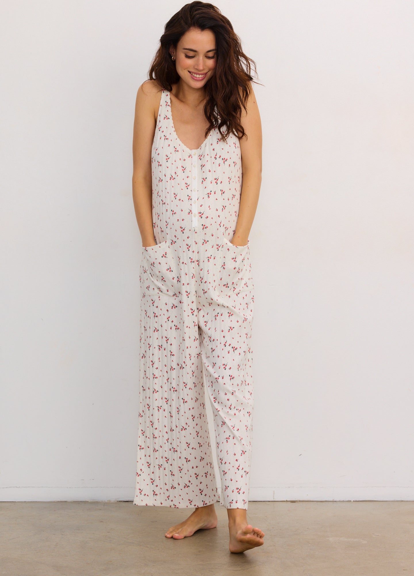 Light pink sleeveless maternity jumpsuit with small floral print, loose fit, and pockets.
