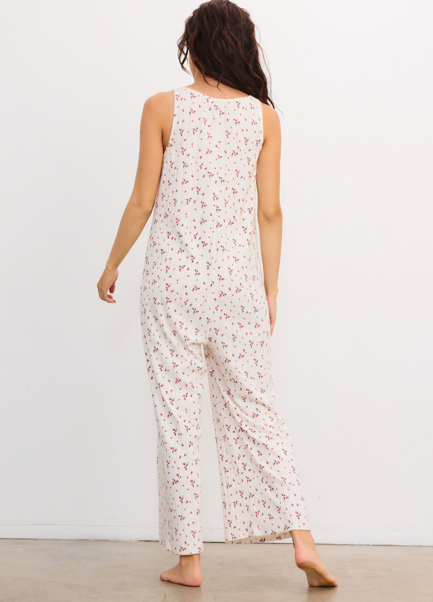 White sleeveless maternity jumpsuit with pink floral print and wide-leg pants.