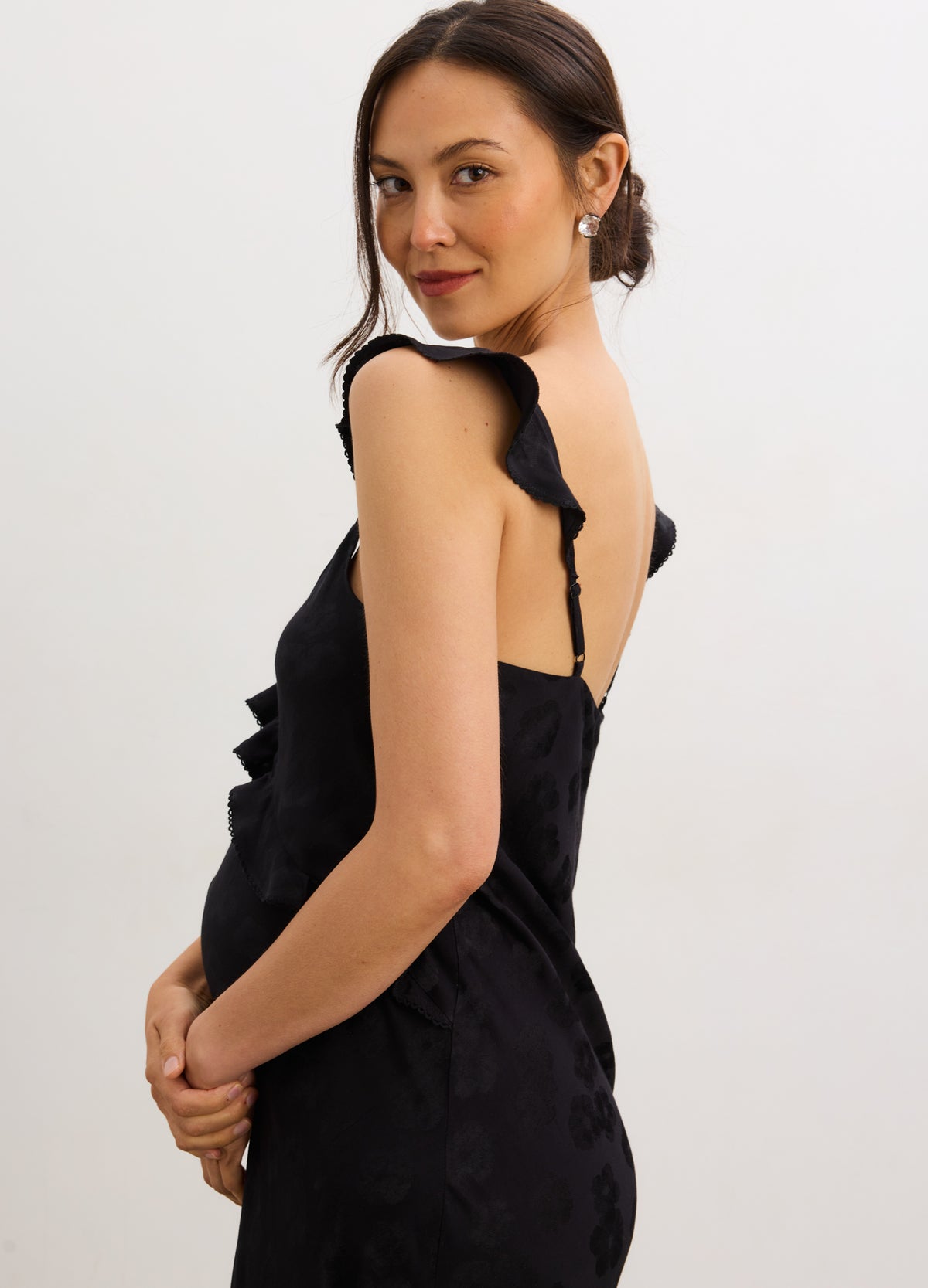 Black jacquard bias maternity slip dress with ruffle straps and open back on pregnant model.