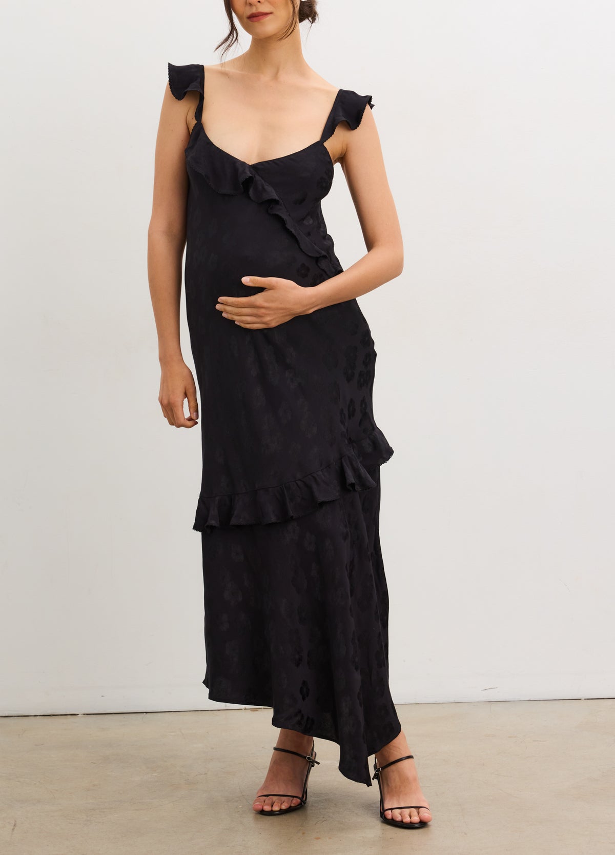 Black jacquard maternity slip dress with ruffle details and adjustable shoulder straps.