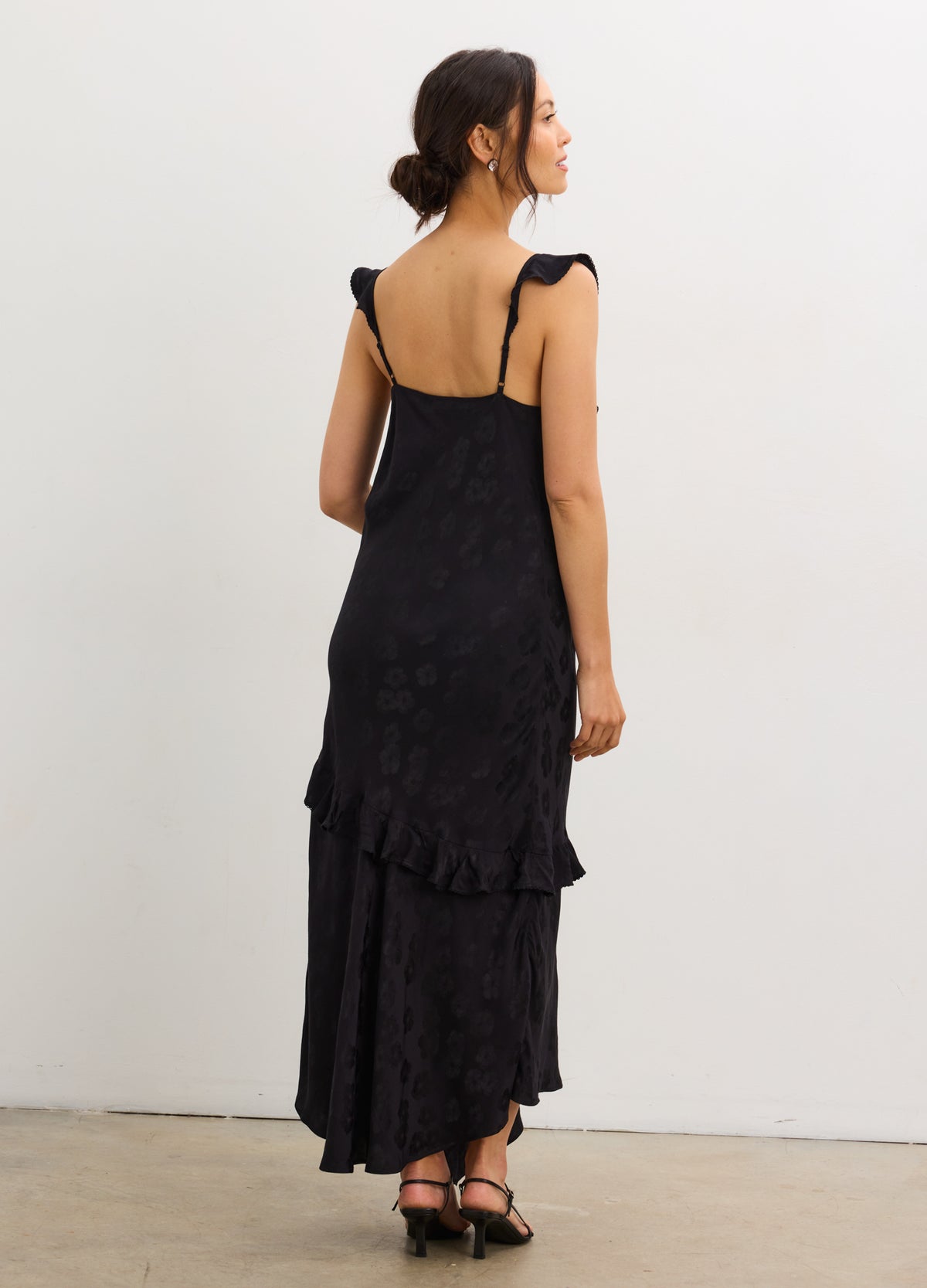 Black jacquard maternity slip dress with adjustable tie straps and tiered ruffle hem.