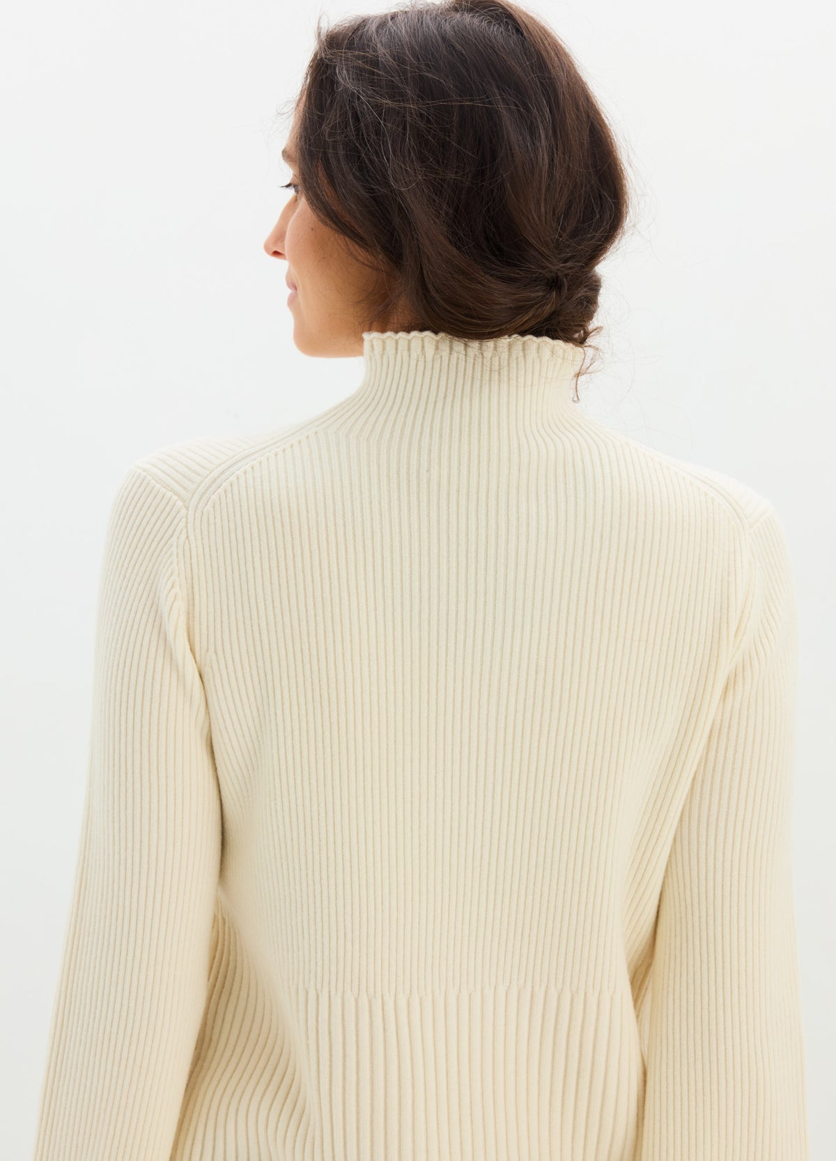 Cream ribbed knit turtleneck sweater with subtle ruffle edge, designed for maternity fit.