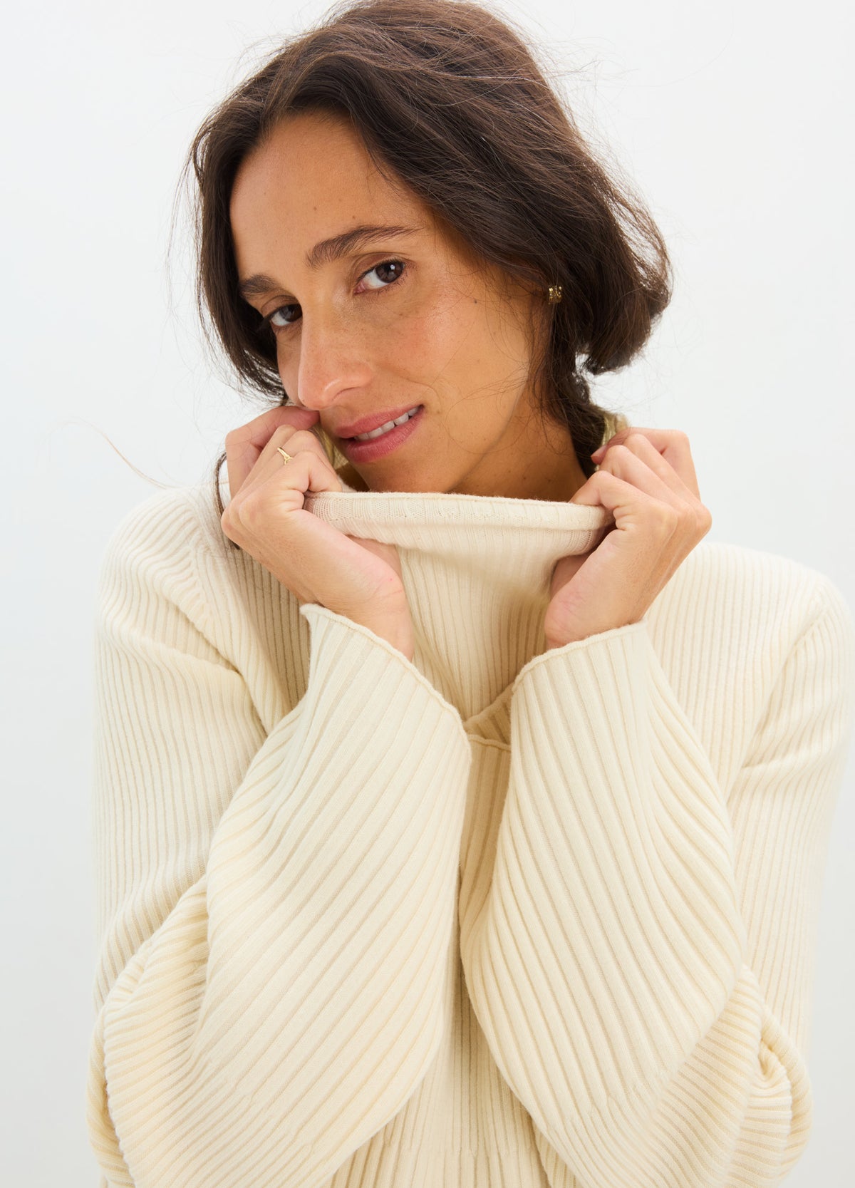 Cream-colored ribbed knit maternity turtleneck with long bell sleeves, worn by pregnant model.