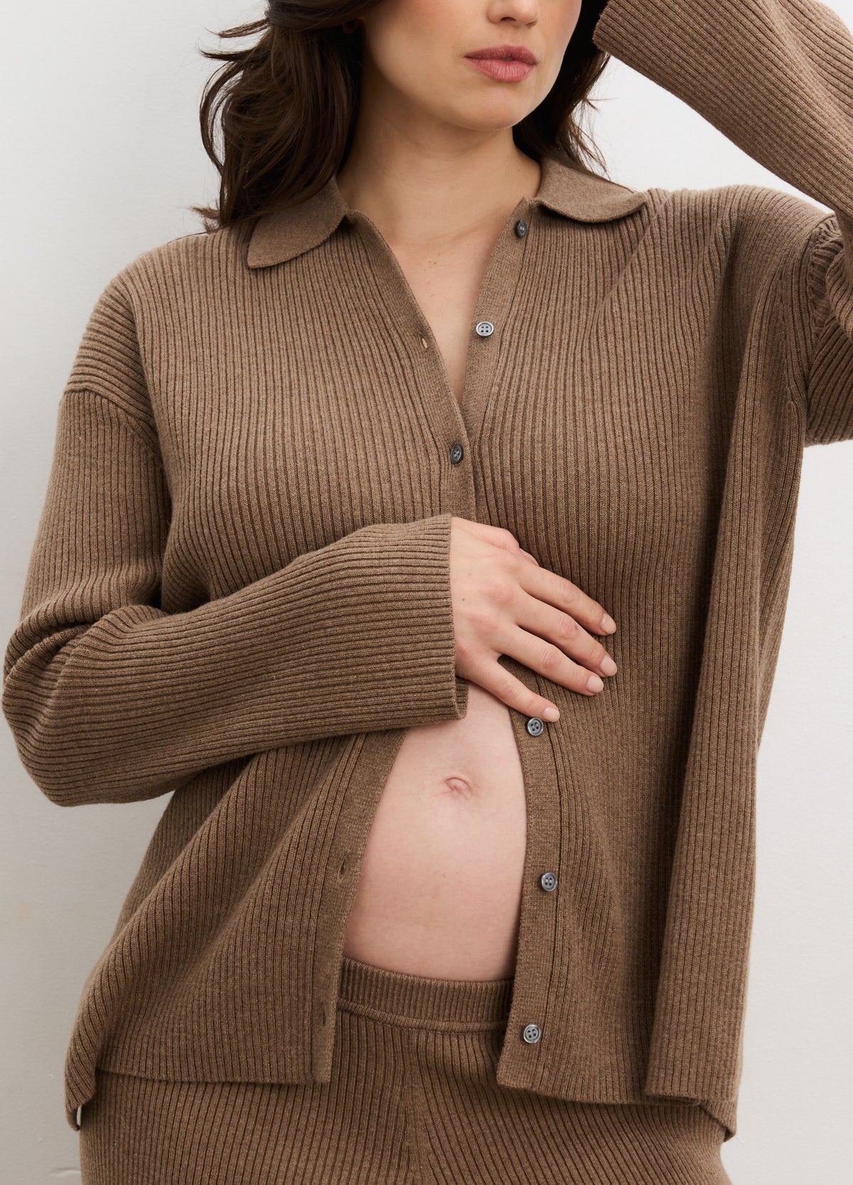 Brown ribbed knit buttondown polo with long sleeves and soft collar, styled open over maternity wear.