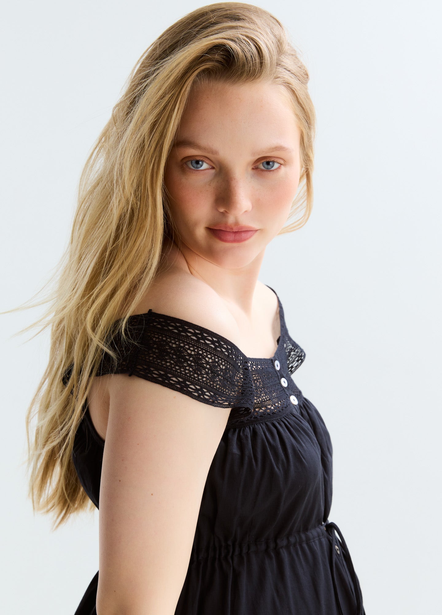 Black off-shoulder maternity dress with lace detailing and front buttons, flowy fabric.