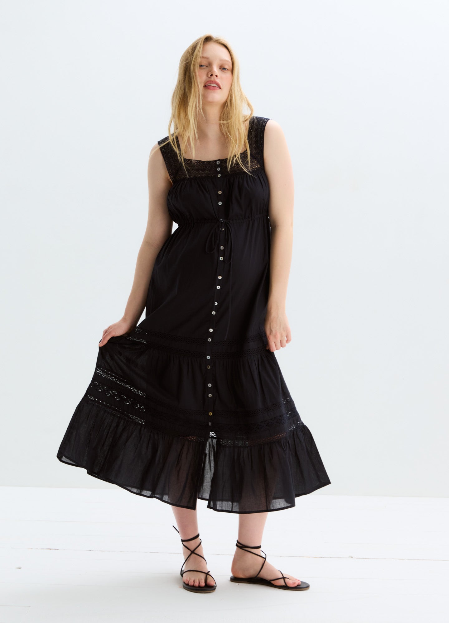 Black sleeveless maternity dress with button-down front and tiered ruffle hem.