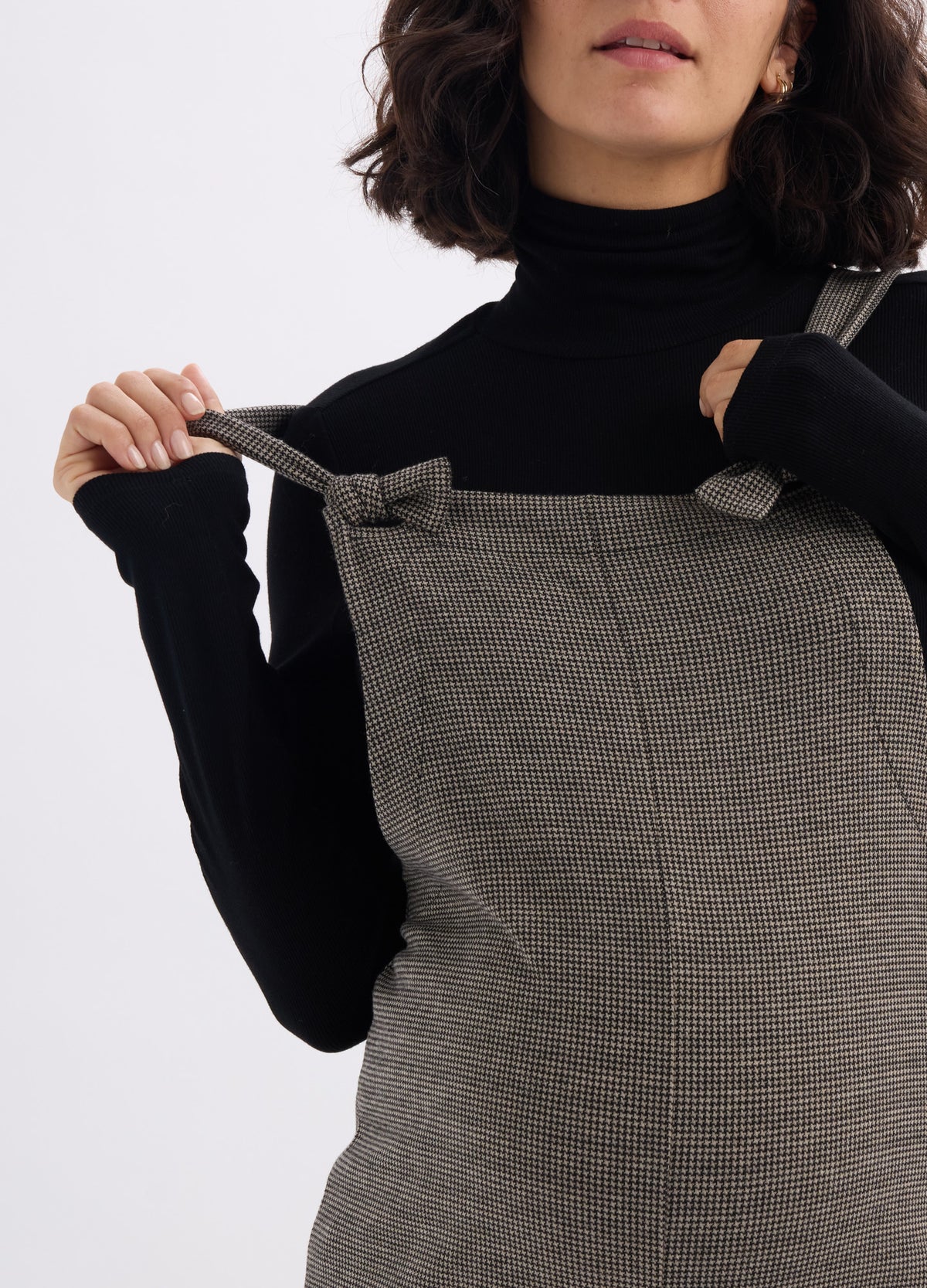 Olive green quilted maternity onesie with adjustable shoulder straps worn over black turtleneck sweater.
