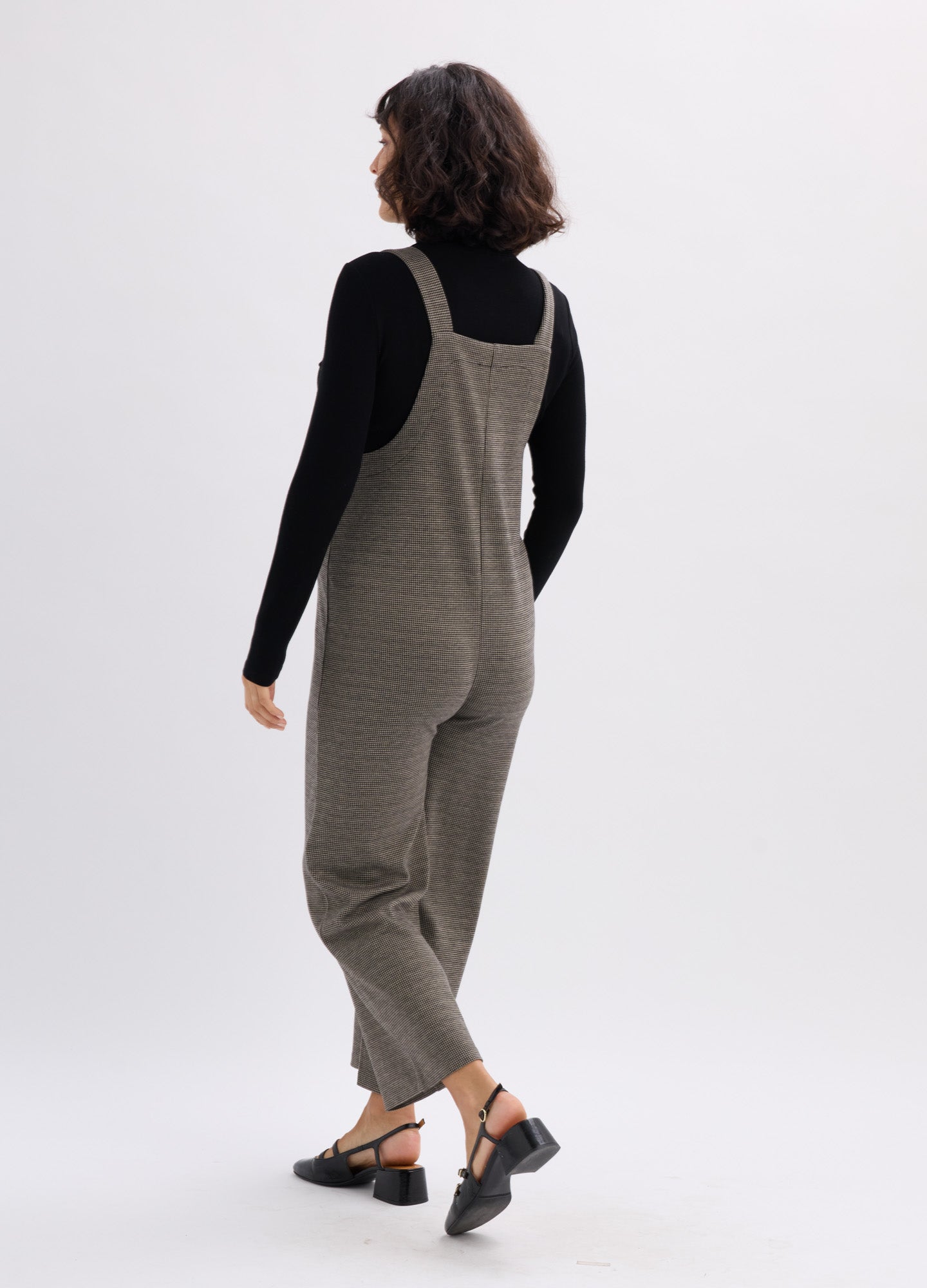 Olive green ribbed knit maternity onesie with adjustable shoulder straps and tapered legs worn over a black long-sleeve top.
