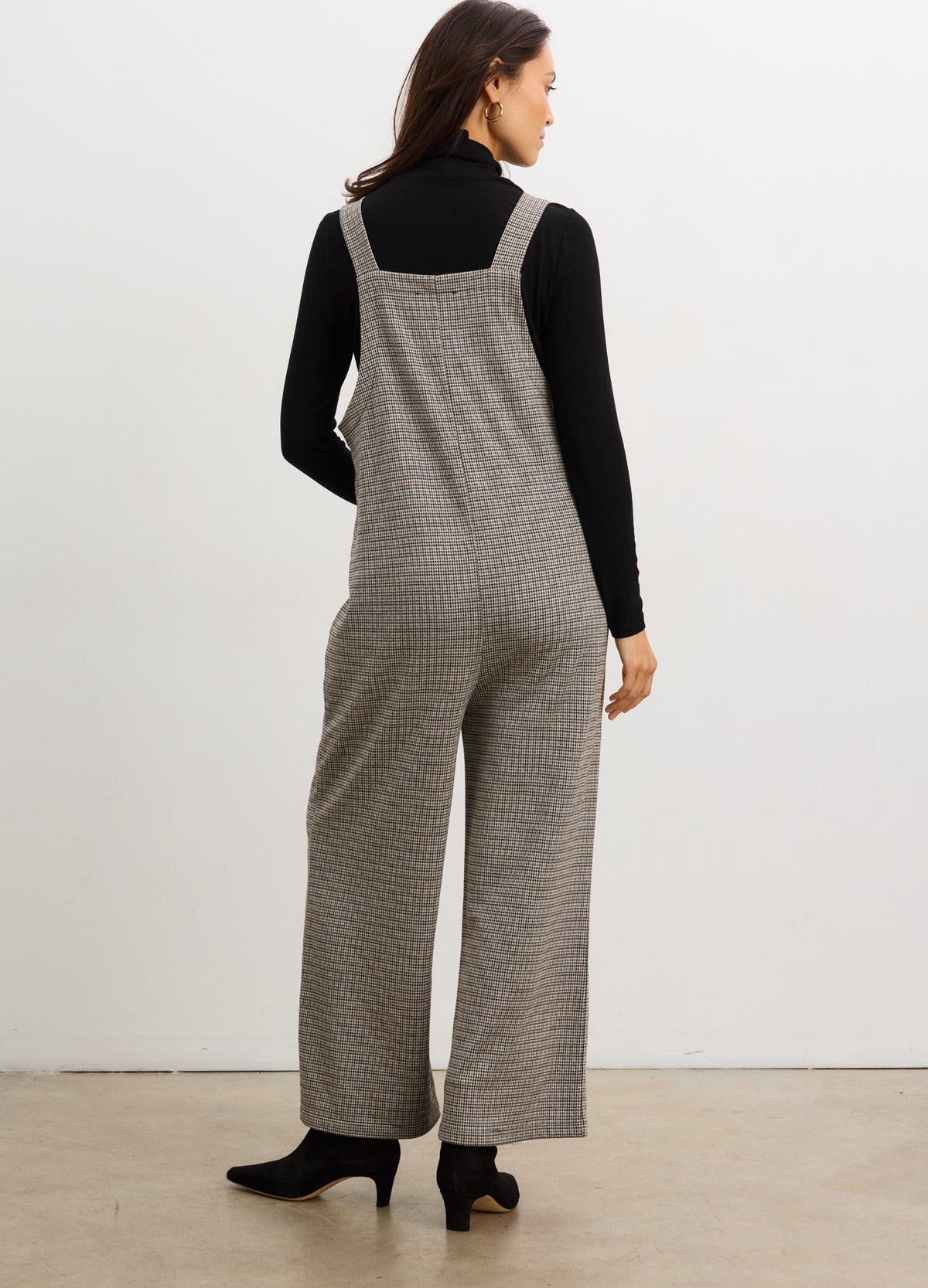 Gray soft stretch maternity jumpsuit with wide legs and adjustable shoulder straps over black fitted turtleneck.