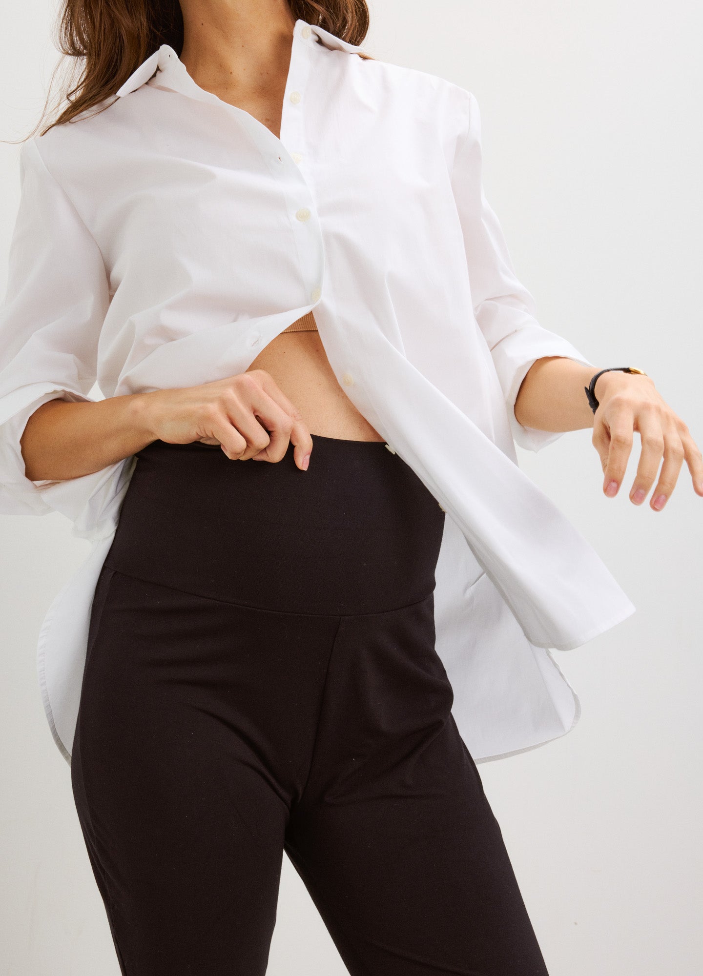 Black high-waisted maternity crop flare leggings with stretchy fabric worn with white button-up shirt.