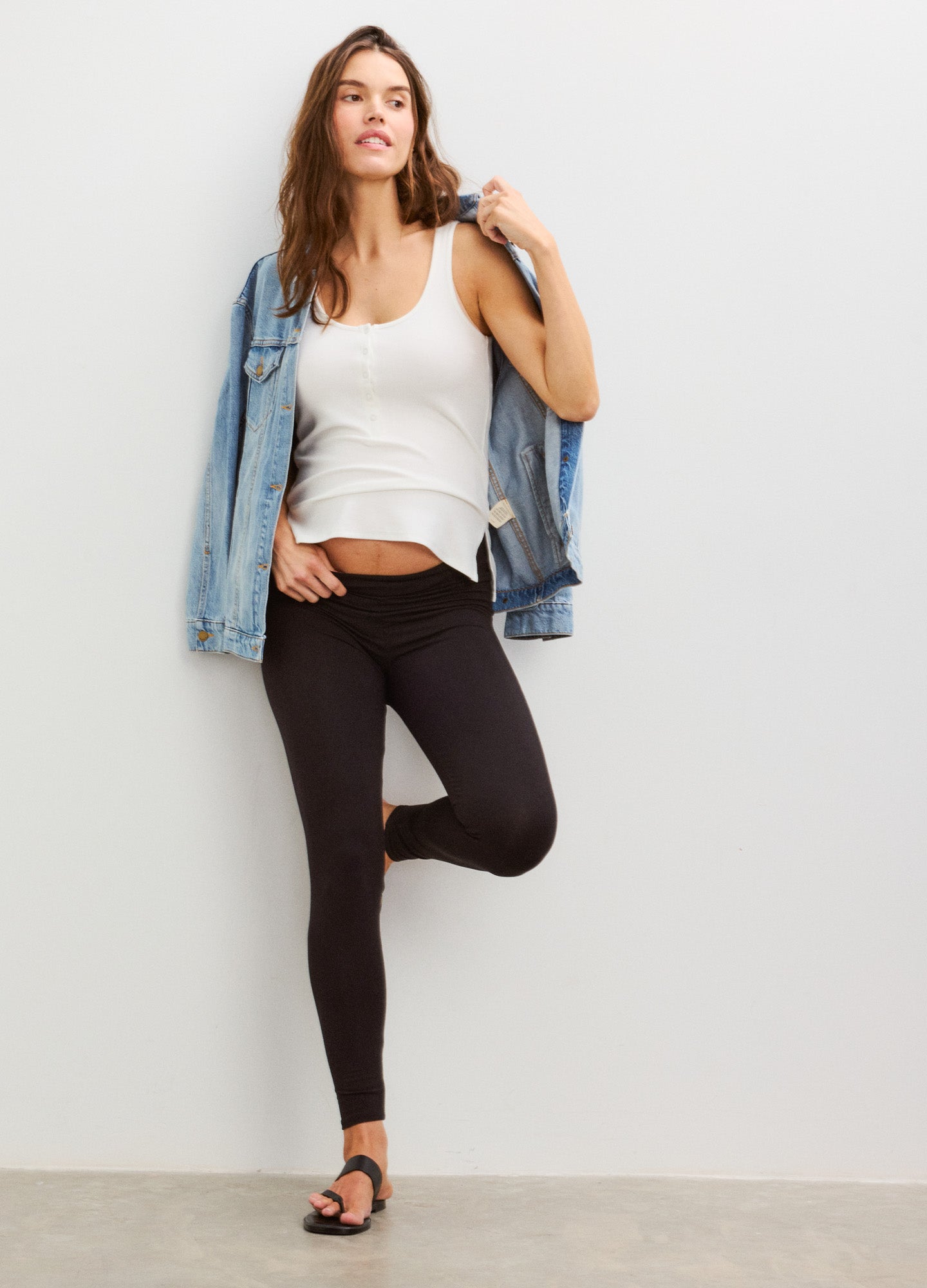 Black maternity leggings with high stretch fabric, paired with a white tank and denim jacket.