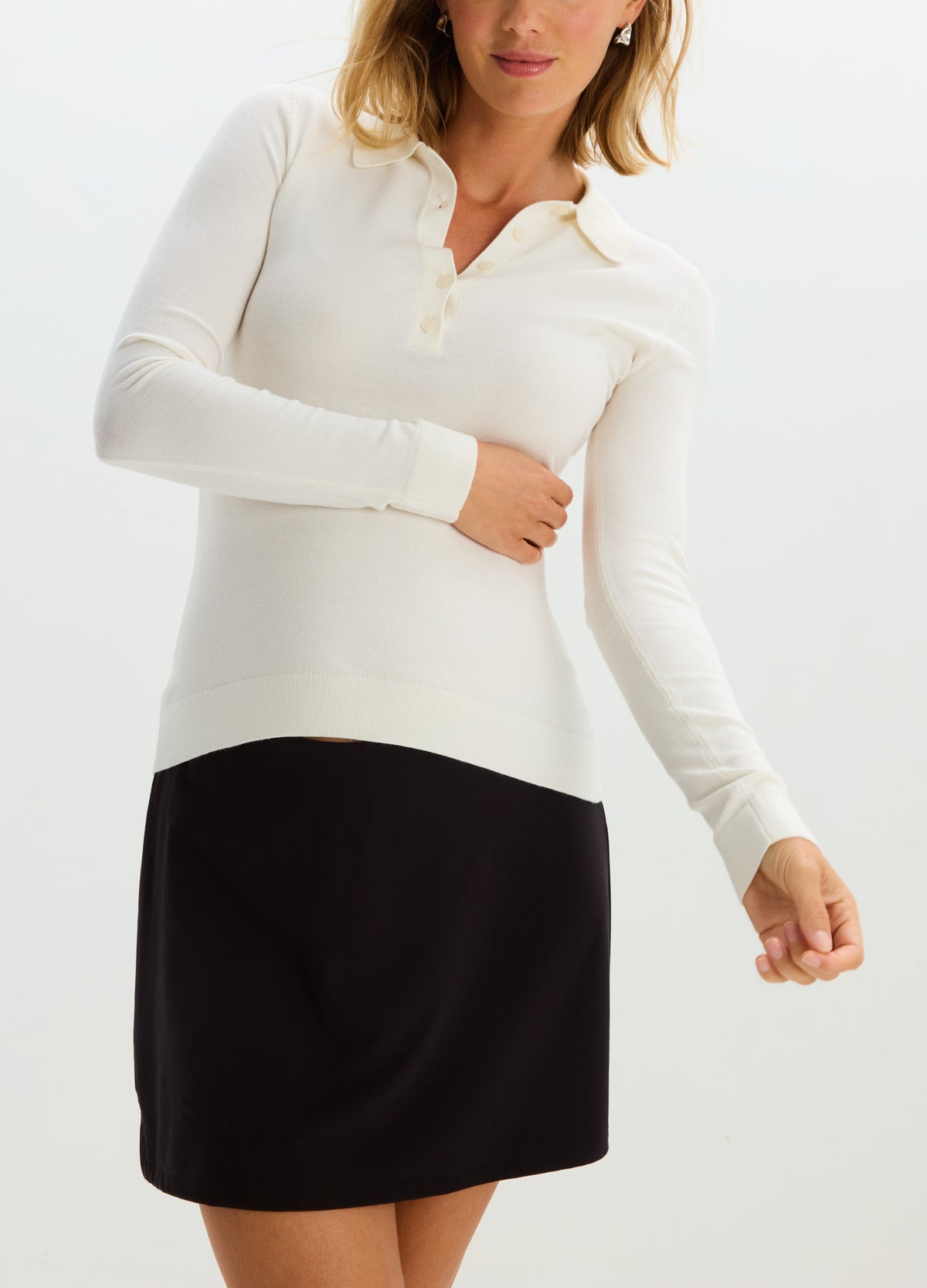 Black maternity skort with a smooth, stretchy fabric designed for pregnant women, paired with a long-sleeve white polo top.