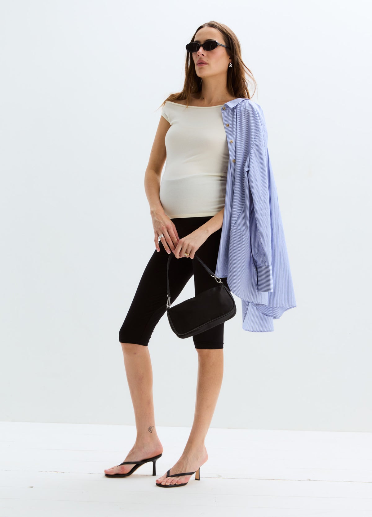Black knee-length maternity capri leggings with a supportive high waistband, styled with a white fitted top and light blue.