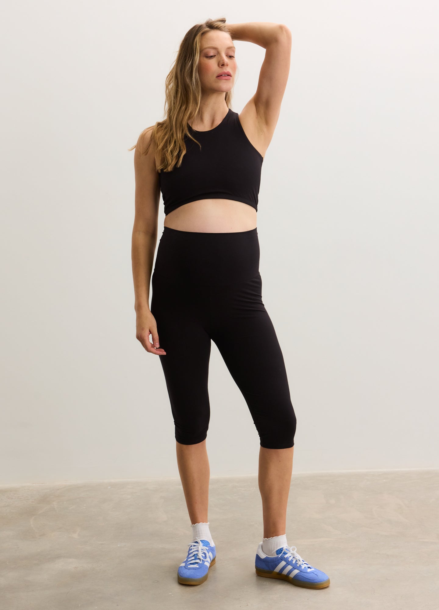 Black cropped racerback tank with a fitted silhouette, designed for maternity wear.