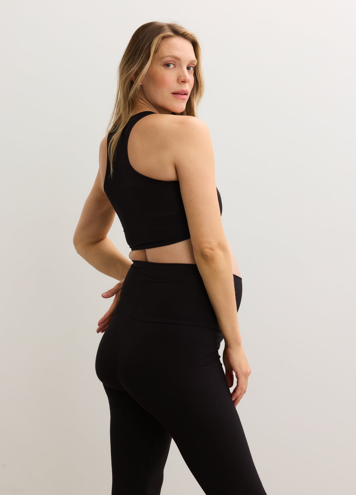 Black stretchy crop racer tank with racerback design, fitted for maternity wear.