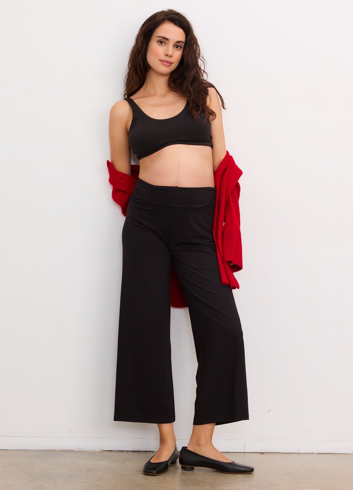 Black maternity crop pants with wide legs, soft stretchy fabric, worn with a black crop tank and red cardigan draped over.