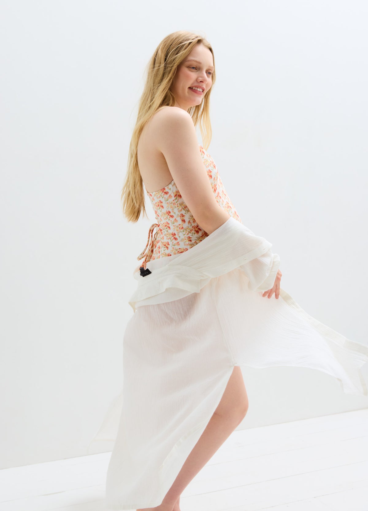 White flowing maternity shirt dress with sleeveless floral bodice, side slit, and lightweight fabric.