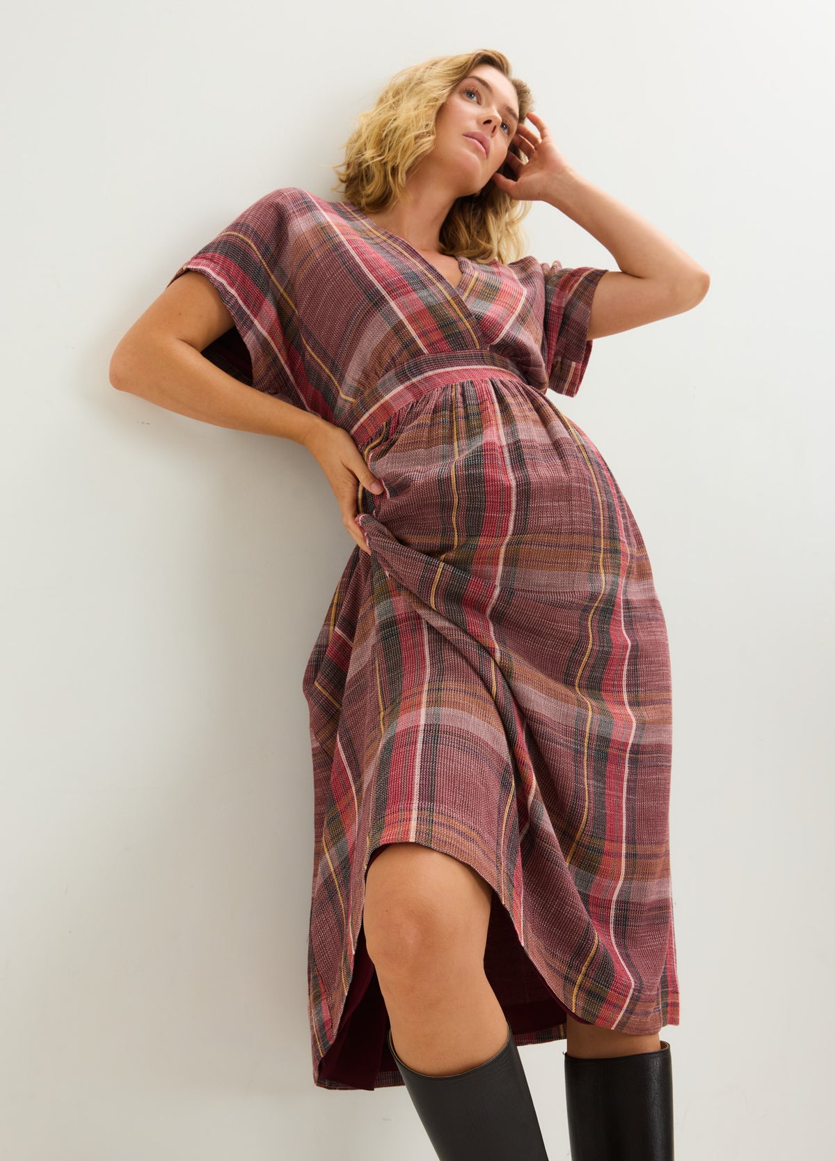 Plaid maternity dress with short sleeves and a V-neckline, designed to accommodate a pregnant belly.