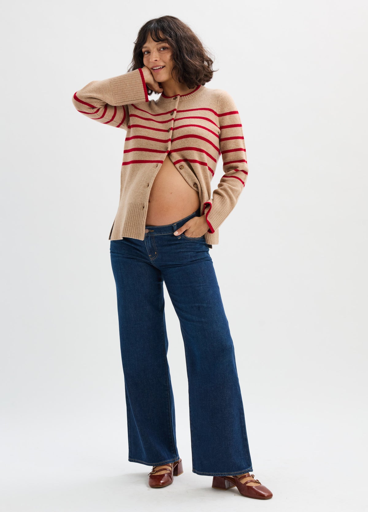 Beige and red striped maternity cardigan with button front, worn open over bare pregnant belly, paired with dark blue.